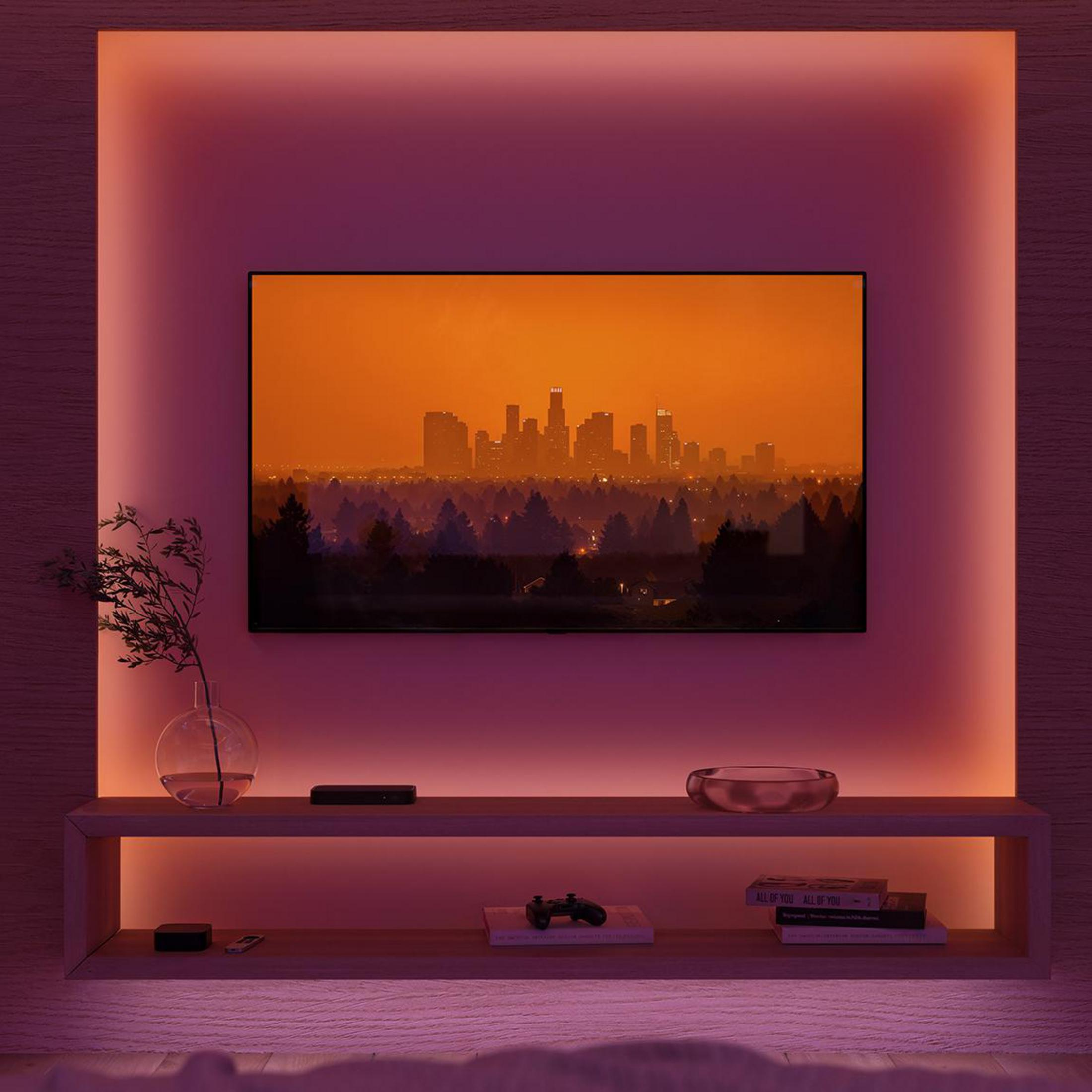 Un televisor muestra el horizonte de una ciudad al atardecer, enmarcado por iluminación ambiental.