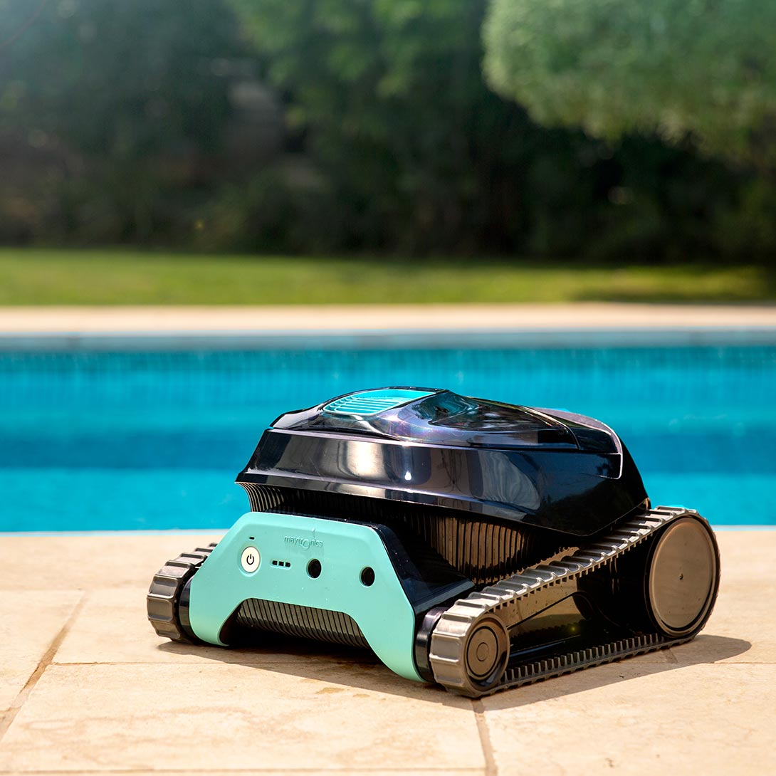 Un robot de piscina negro con detalles turquesa se sienta en el borde.