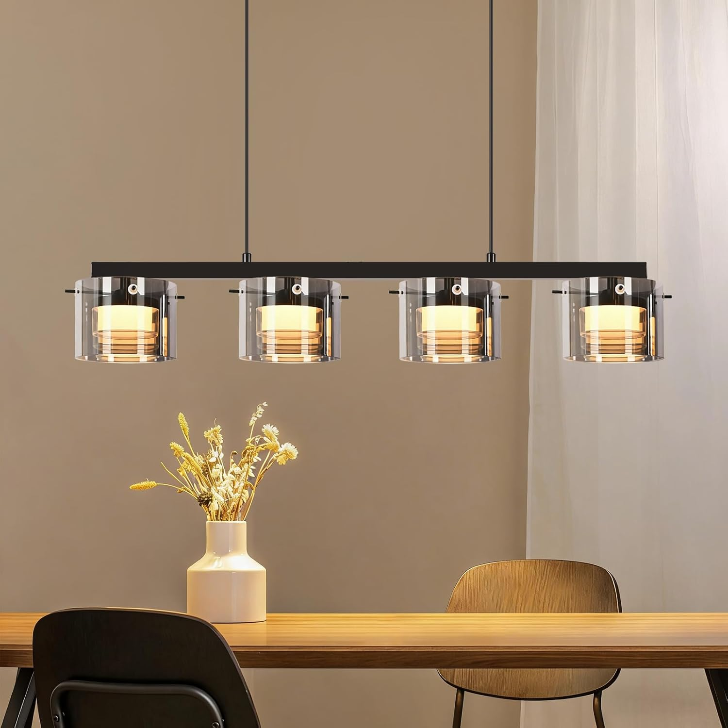 Ein moderner Hängeleuchter mit vier Glaszylindern über einem Holztisch.