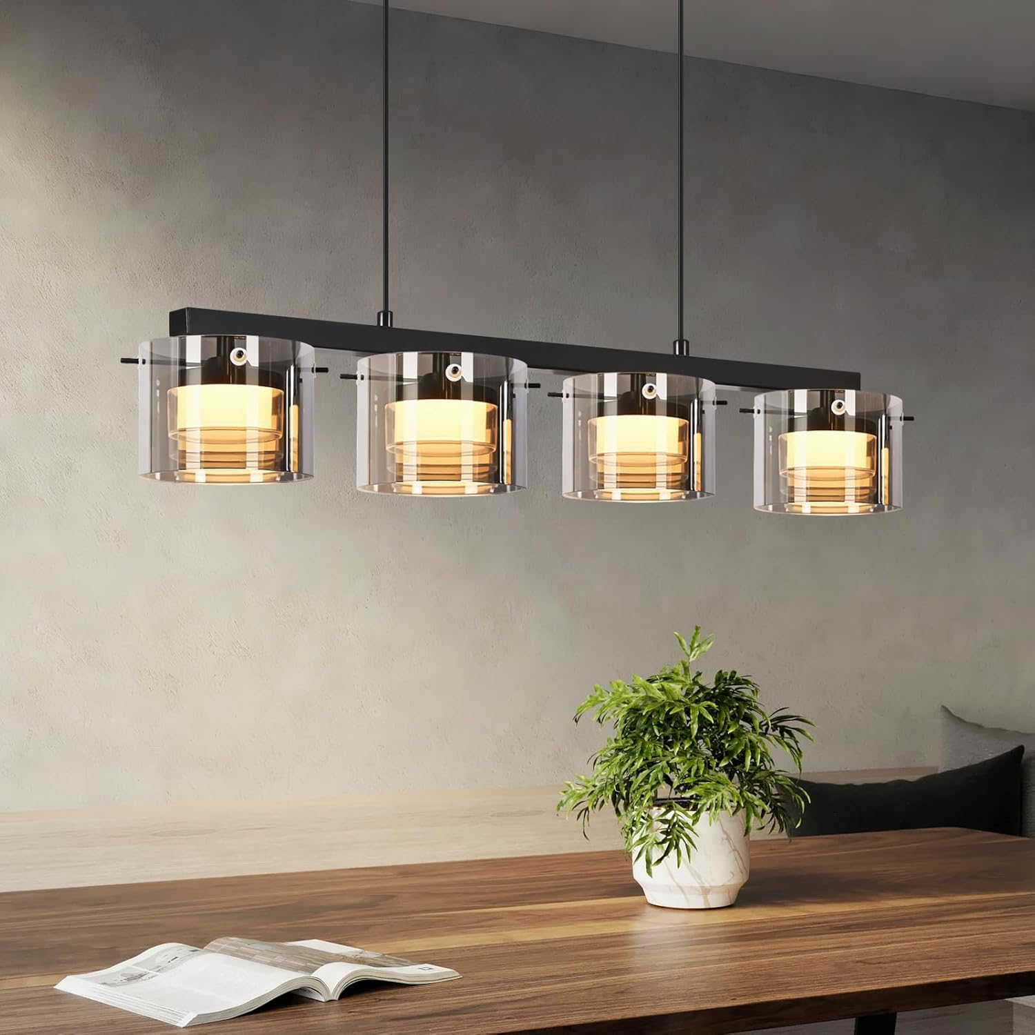 Moderner Pendelleuchter mit vier Glaszylindern über einem Holztisch.