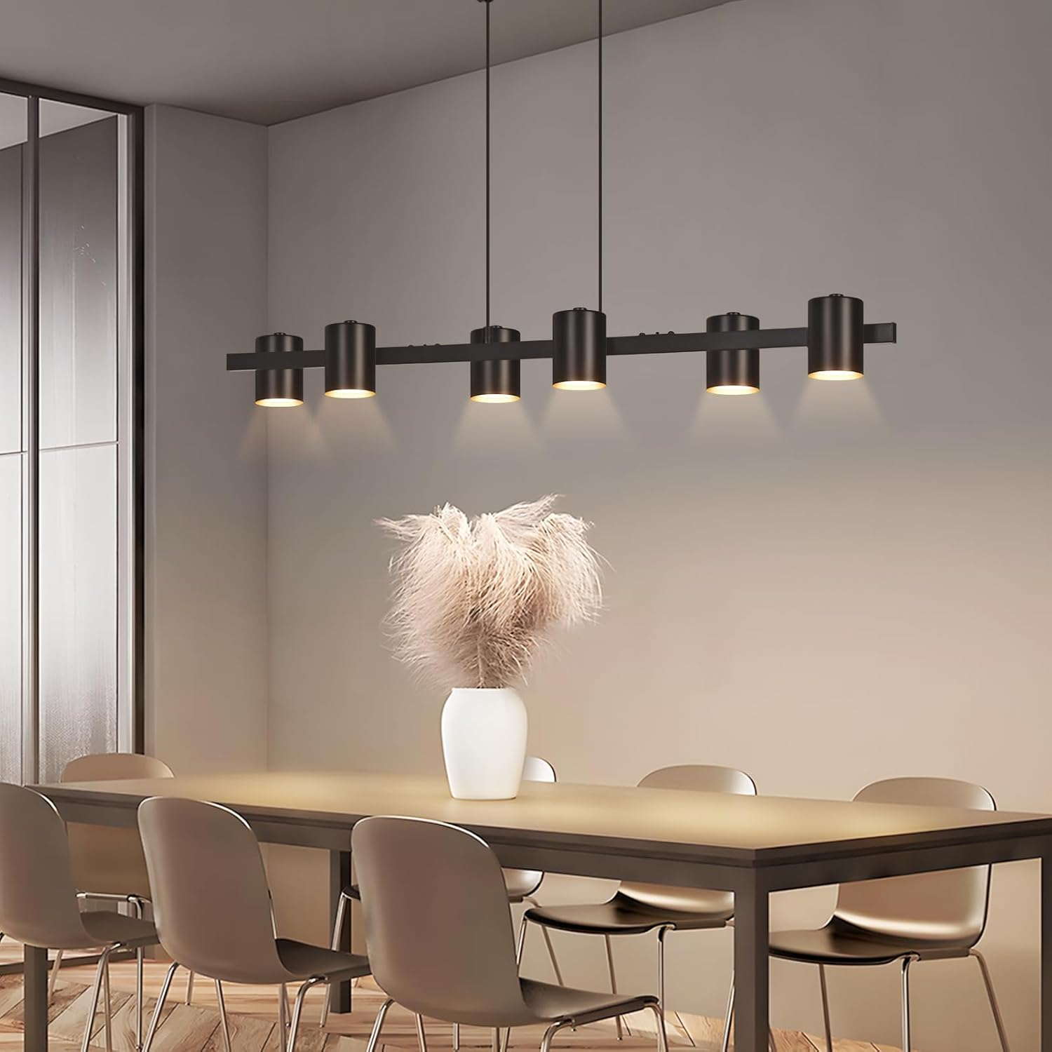 Zona pranzo moderna con lampada a sospensione nera e bouquet in vaso bianco.