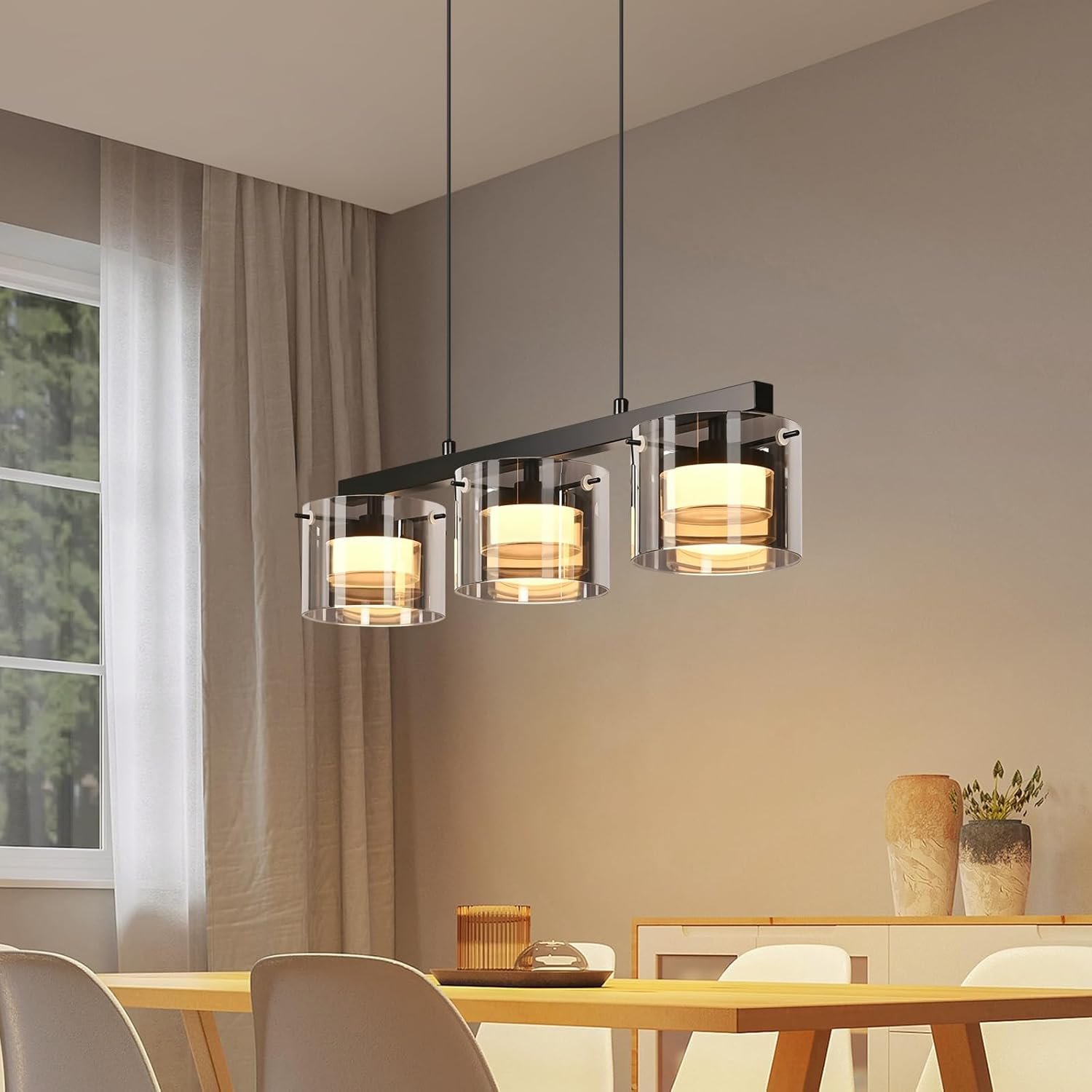 Eine moderne Pendelleuchte mit drei zylindrischen Glaslampenschirmen über einem Holztisch.