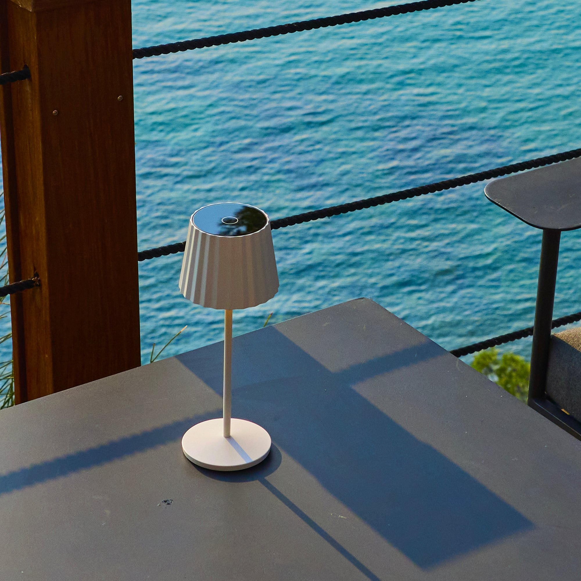 Eine weiße Lampe steht auf einem Tisch mit Blick auf das Meer.