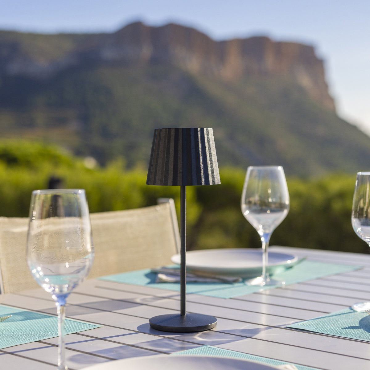 Ein kleiner schwarzer Tisch mit Gläsern und einem Berg im Hintergrund.