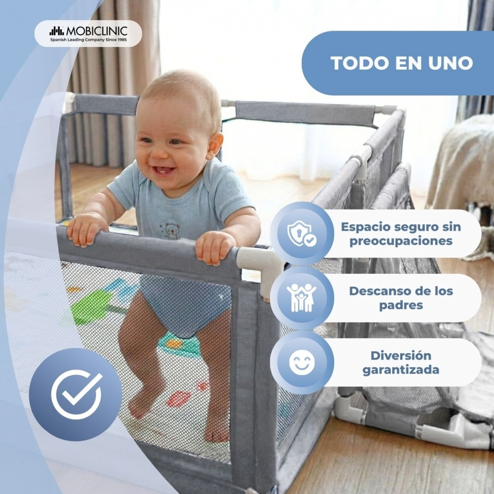 Un bebé sonriente está en un corralito gris. "Todo en uno" está arriba.