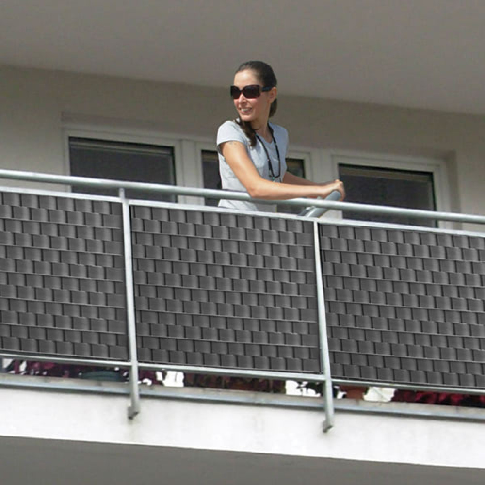 Kobieta na balkonie opiera się o balustradę z osłoną przeciwwiatrową.