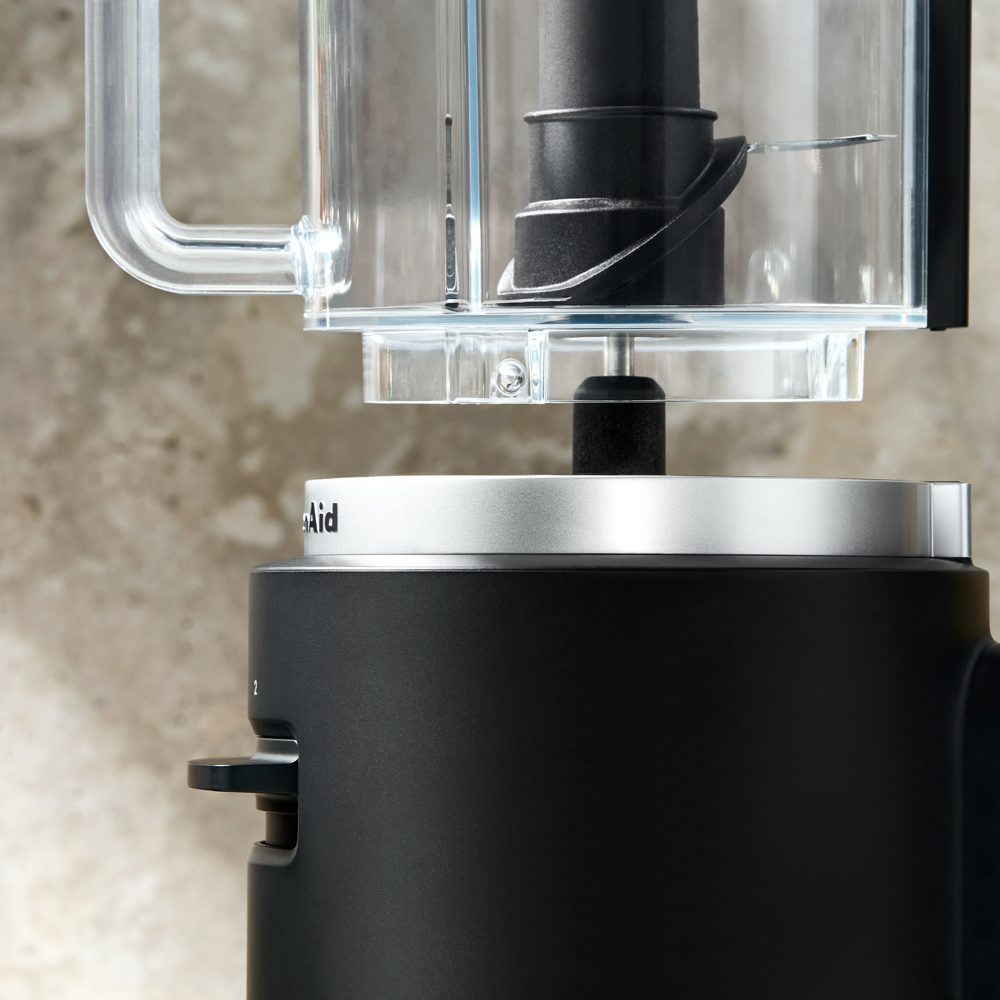 Un robot da cucina KitchenAid nero con coperchio trasparente e lama. Primo piano.