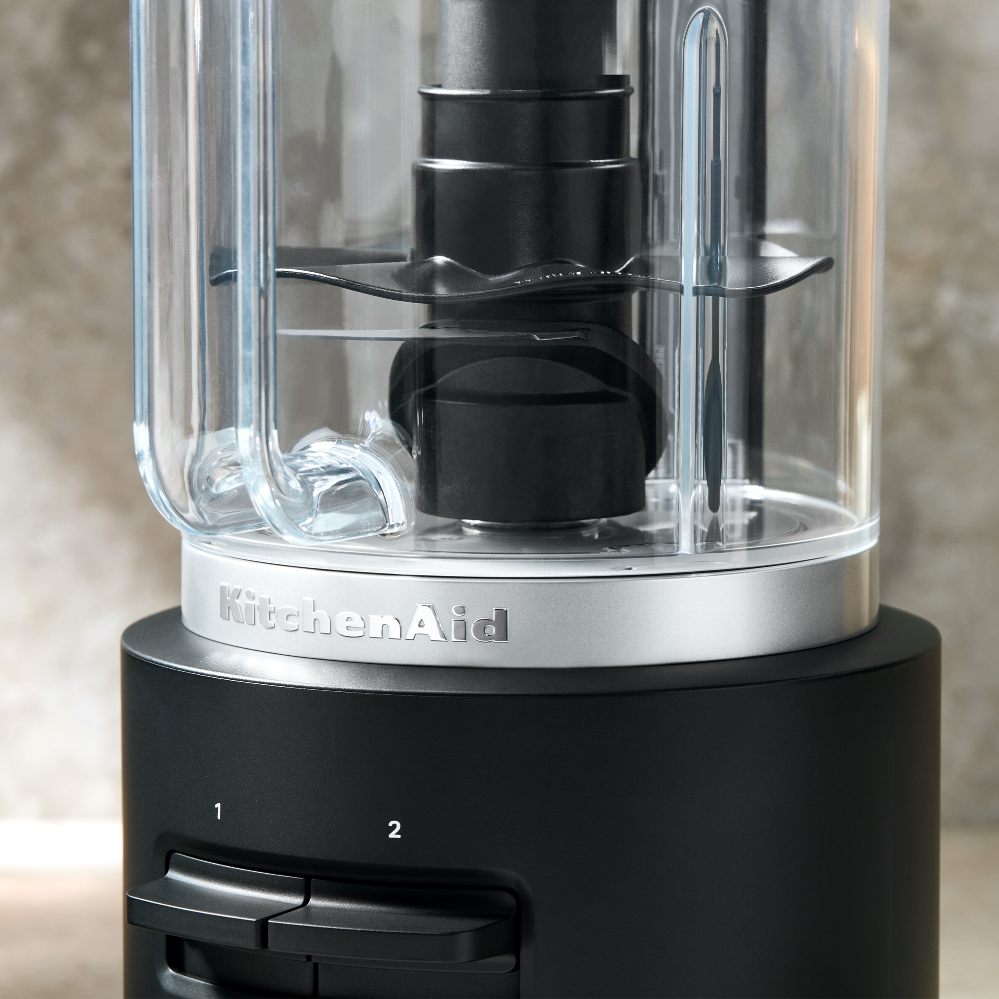 Primo piano di un tritatutto KitchenAid nero con ciotola trasparente e logo argentato.