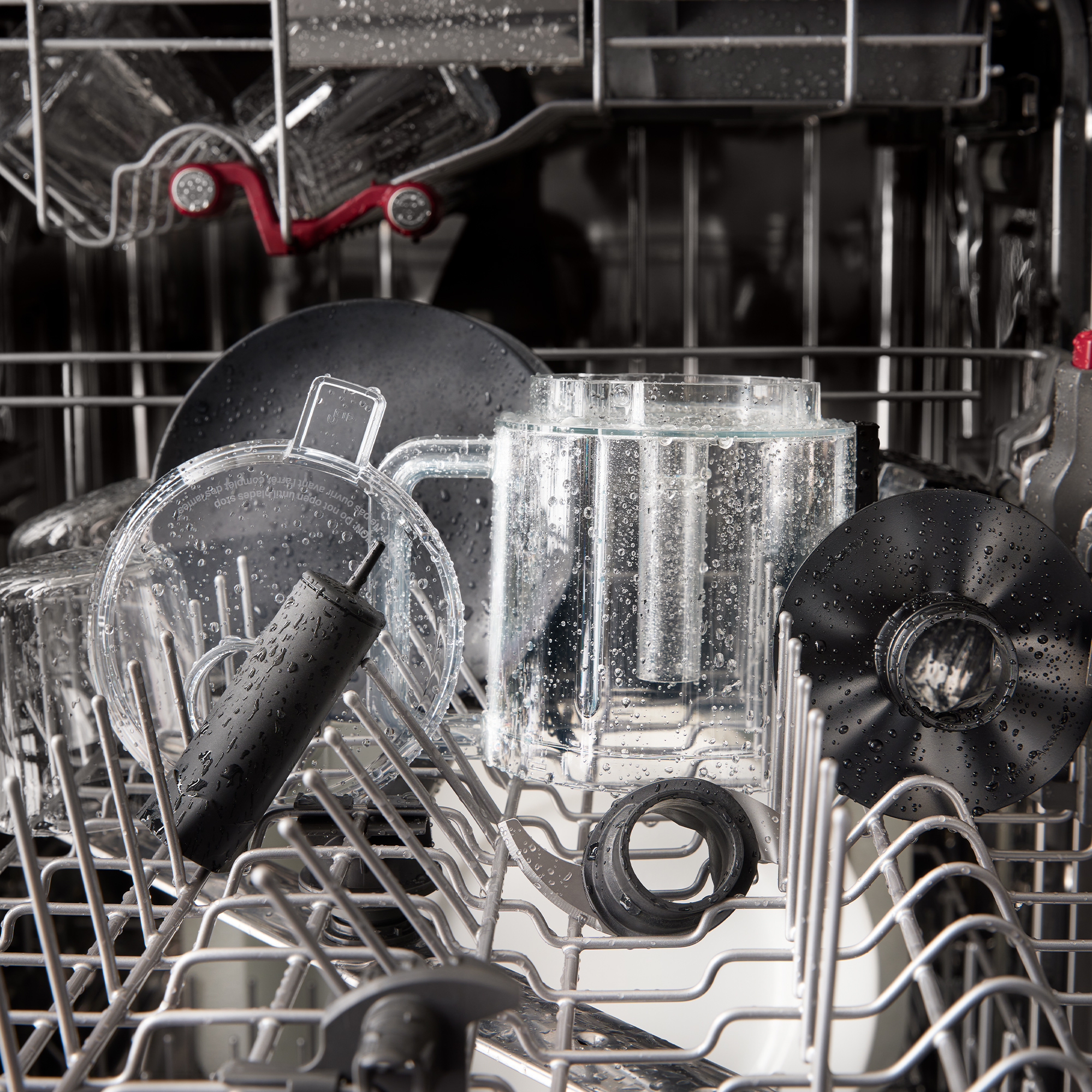 Utensili da cucina inzuppati d'acqua e un'asta nera in una lavastoviglie.