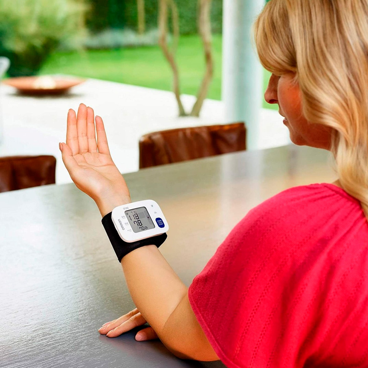 Kobieta mierzy ciśnienie krwi ciśnieniomierzem nadgarstkowym.