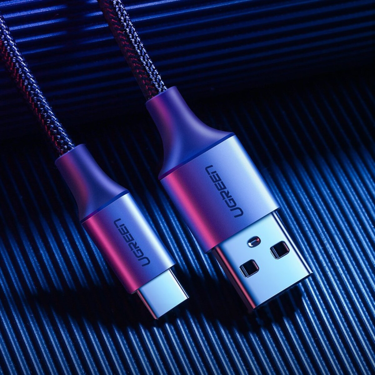 Kabel USB-C i USB-A ze srebrnymi złączami na niebieskim tle.