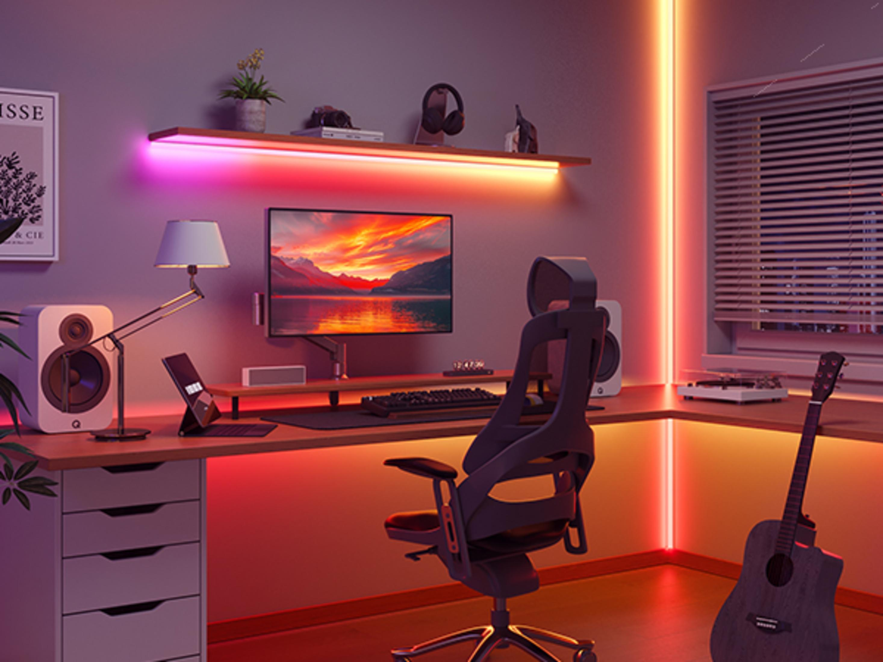 Una scrivania con monitor, chitarra e sedia da gaming, illuminata da luci al neon.