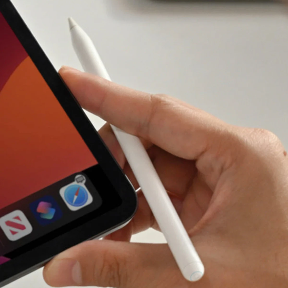 Una mano tiene uno stilo bianco accanto a un tablet che mostra icone di app.