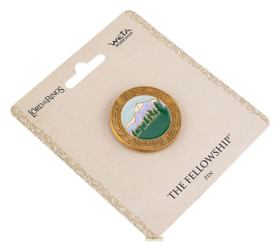 Goldene Anstecknadel mit Herr der Ringe-Motiv: Berg, Bäume, Figuren. Auf Karte.
