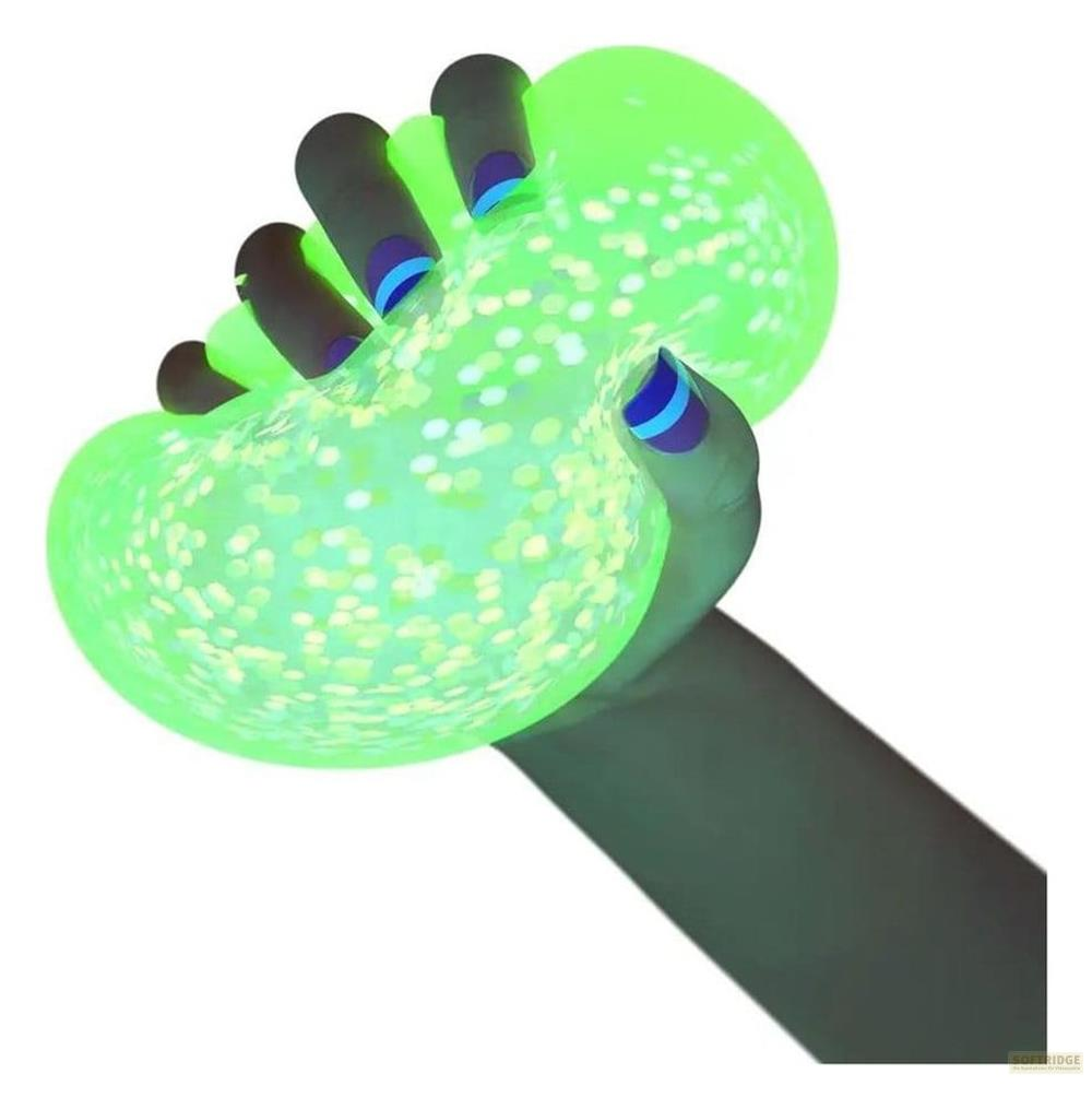 Una mano sostiene una bola verde brillante con purpurina, iluminada por luz UV.