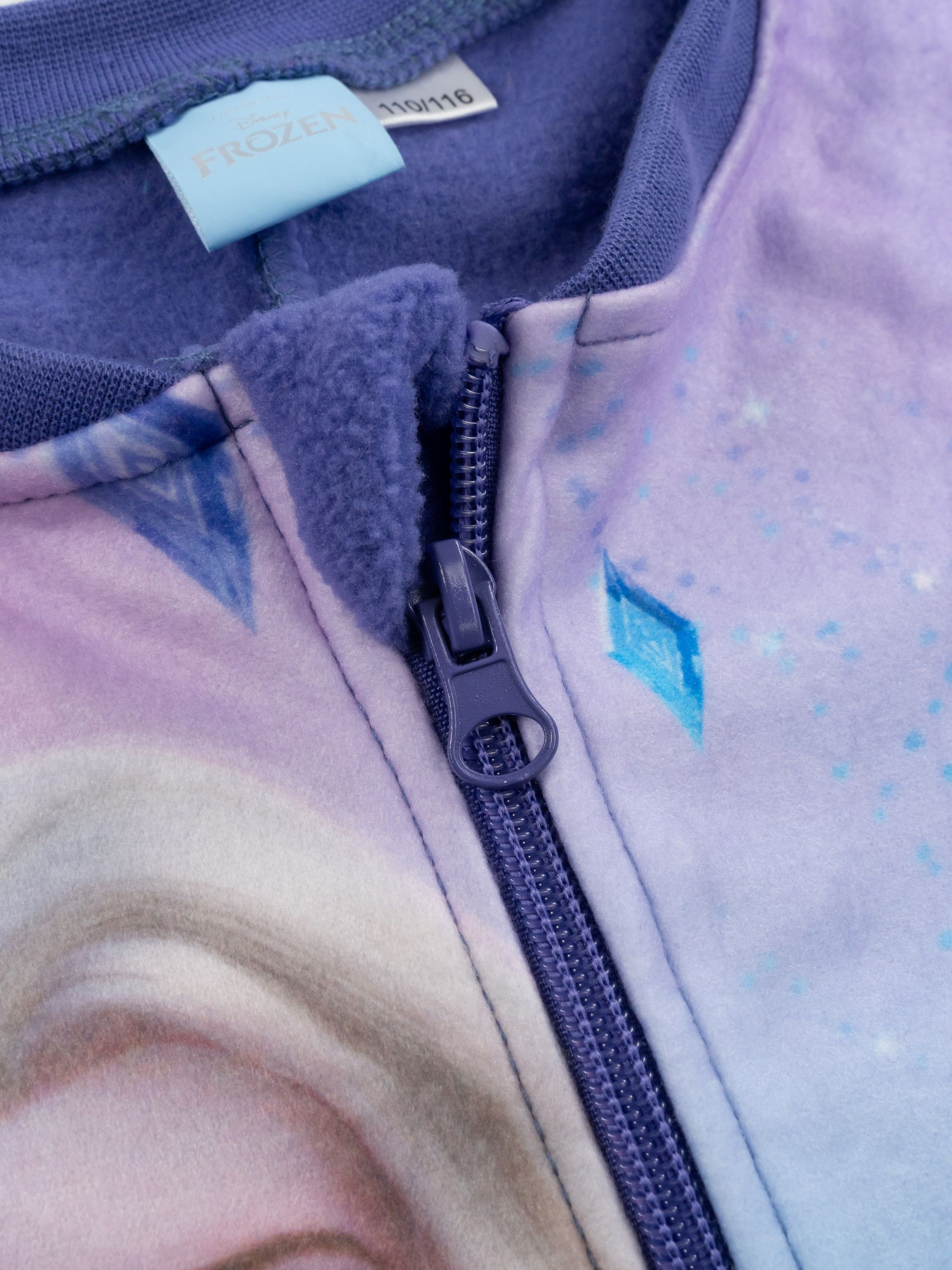 Ein lila Reißverschluss-Pullover mit Frozen-Motiv und Eisblumen.