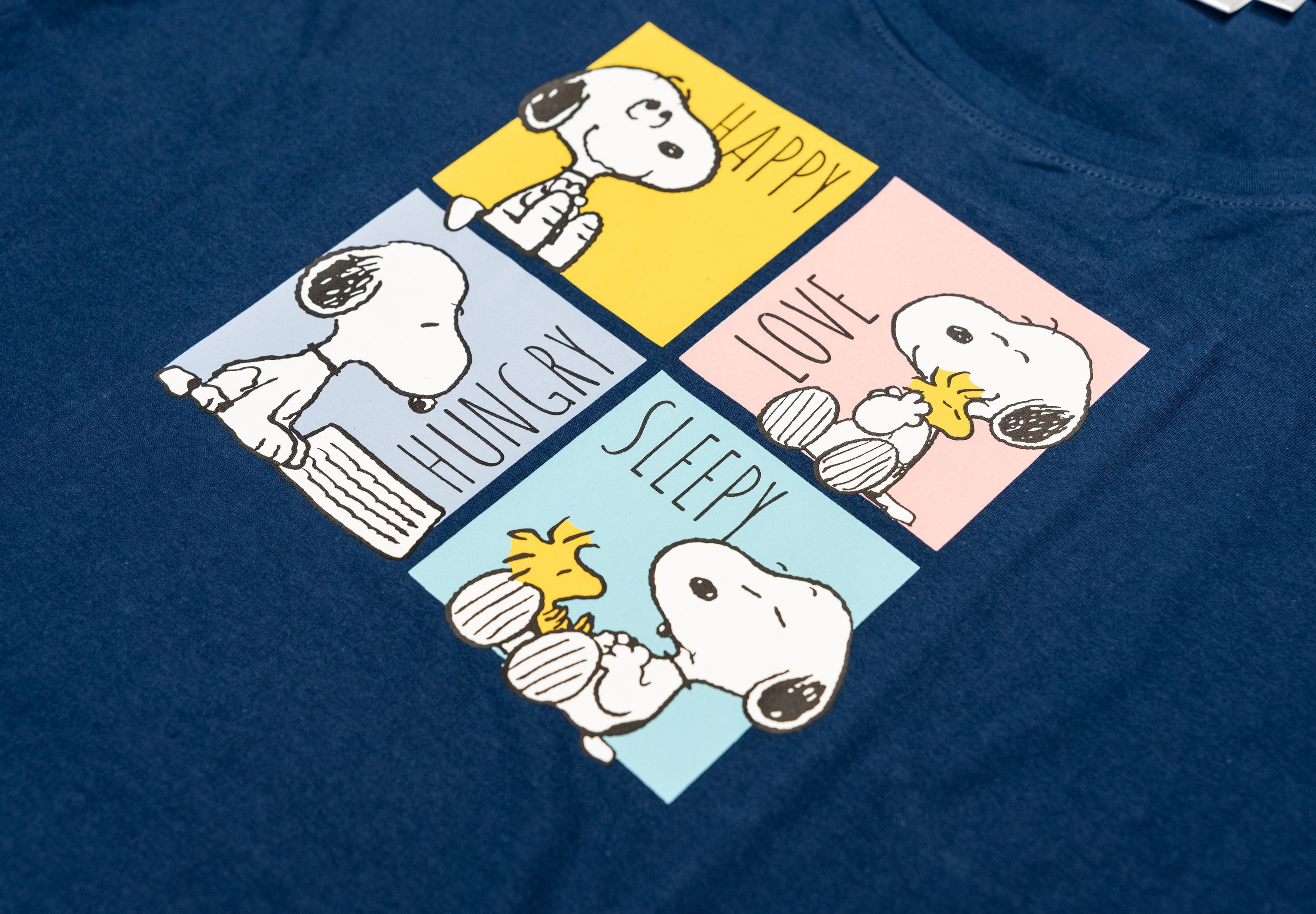 Snoopy und Woodstock auf einem dunkelblauen T-Shirt mit vier Feldern: glücklich, hungrig, Liebe, schläfrig.