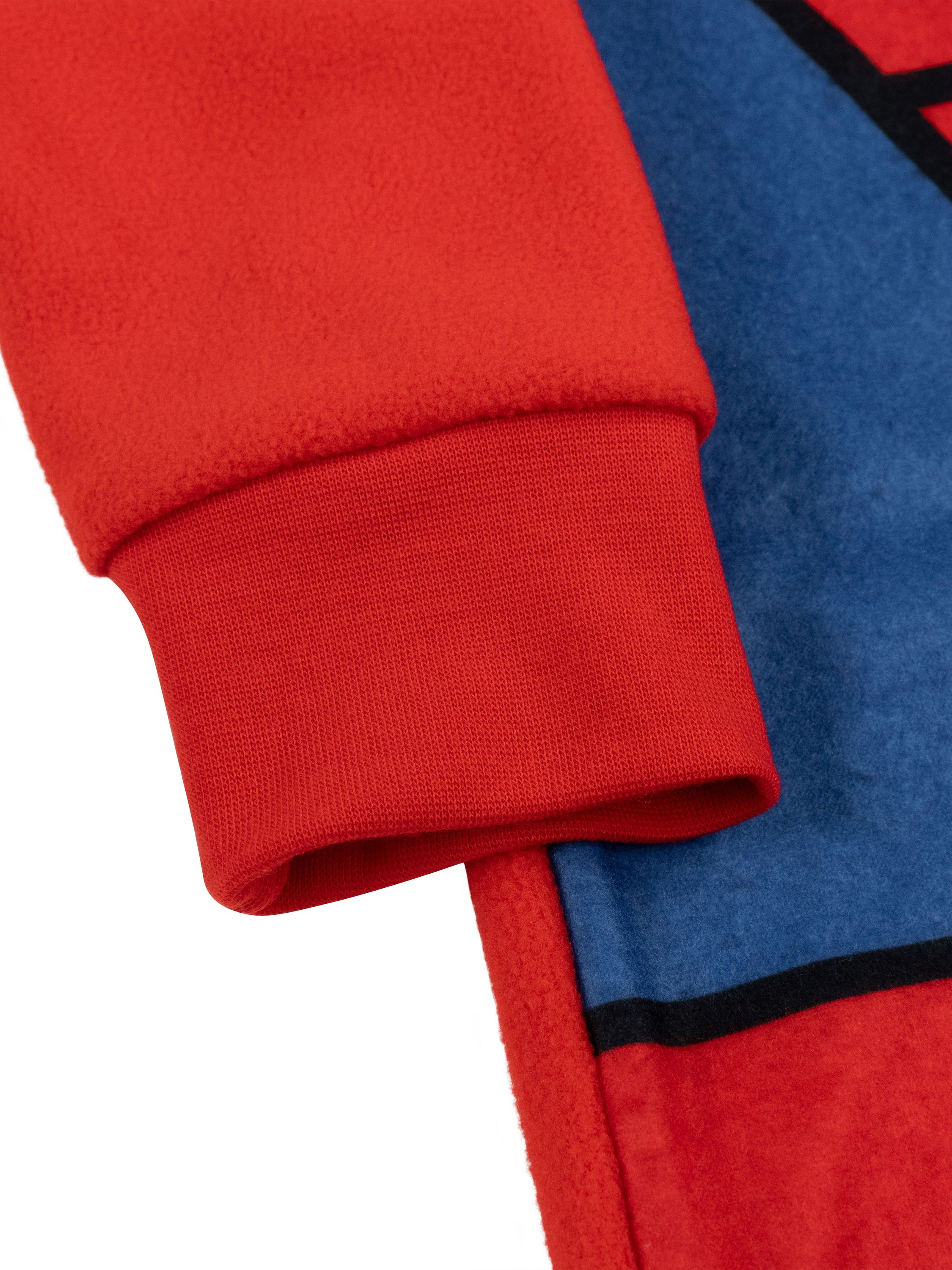 Detailaufnahme eines roten Ärmelbündchens, das mit einem blauen Stoff verbunden ist.