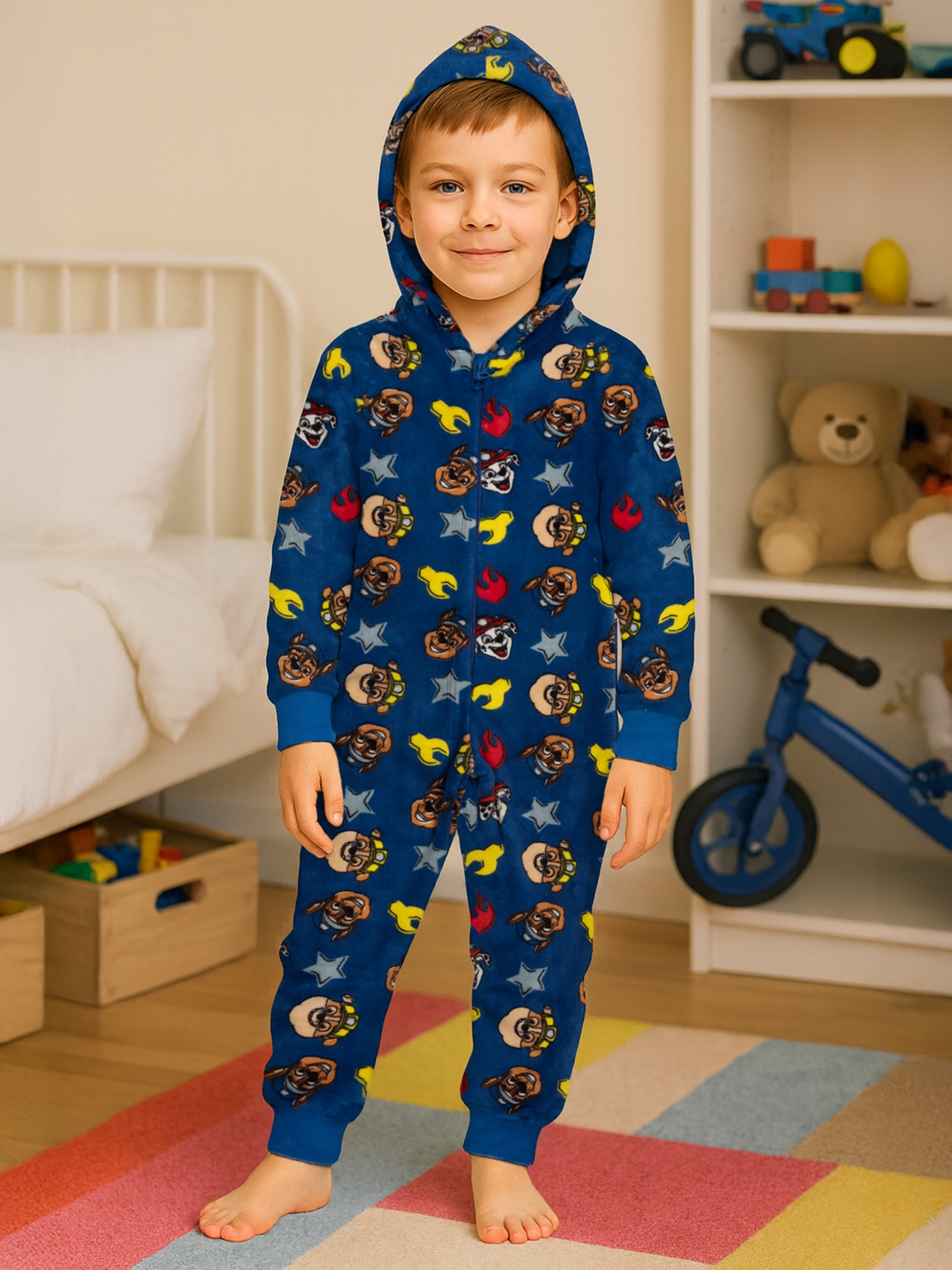 Junge in blauem Pyjama mit Paw Patrol Motiv, steht im Zimmer.