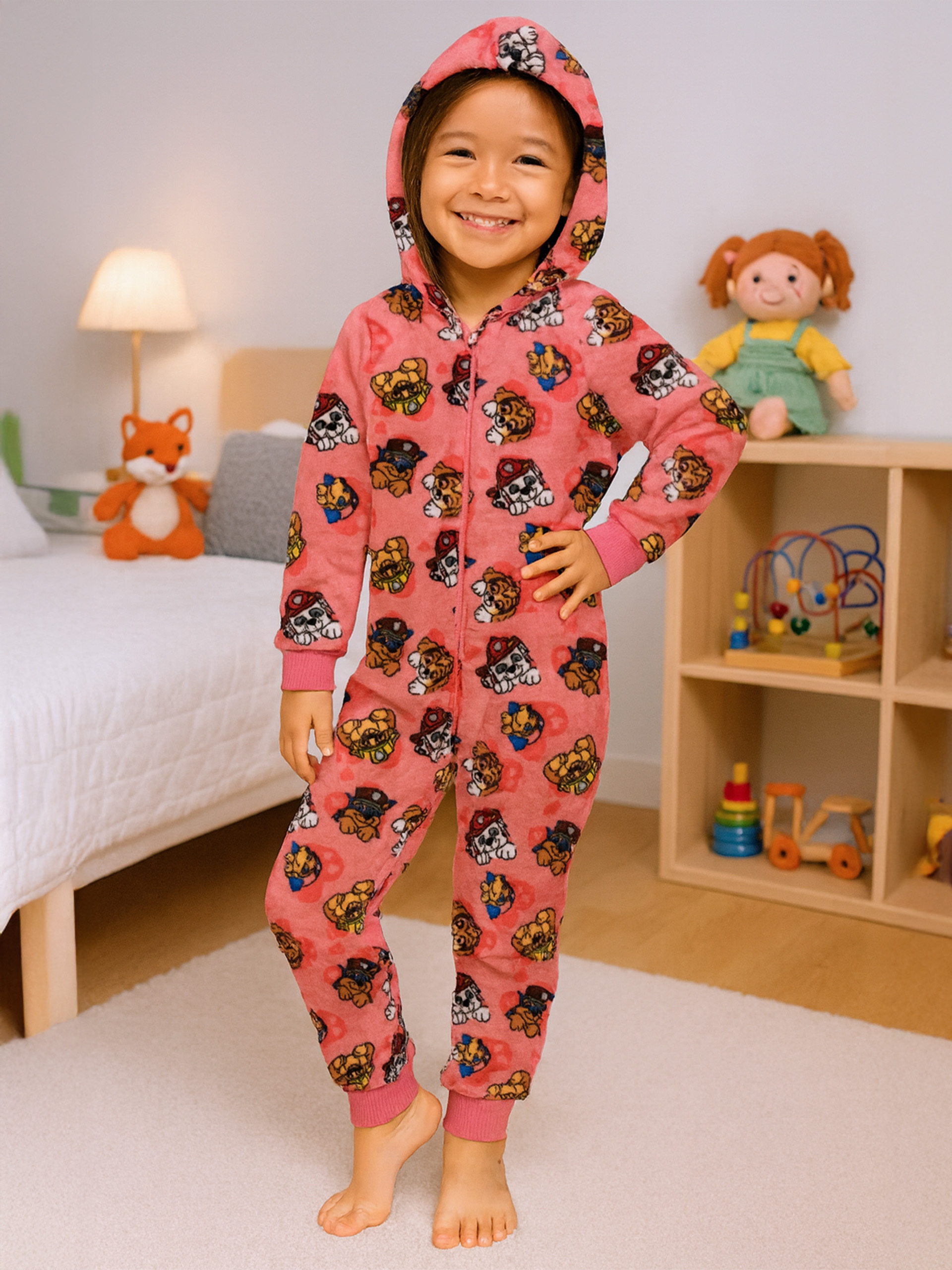 Ein Mädchen in einem rosa Pyjama mit Paw Patrol Motiv lächelt.