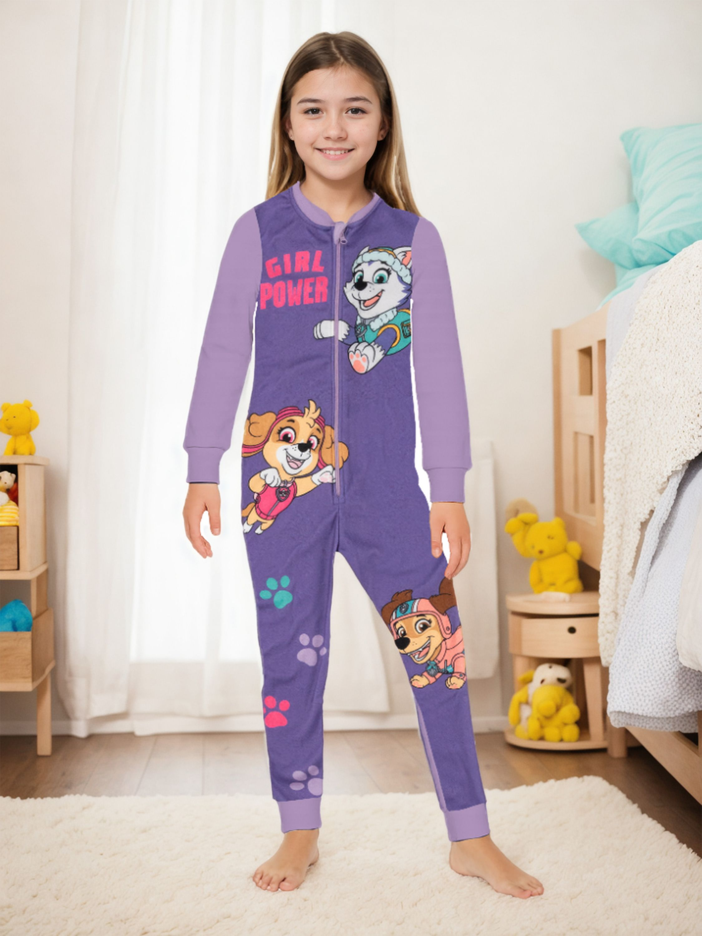 Mädchen in lila Schlafanzug mit Paw-Patrol-Aufdruck steht auf einem Teppich.