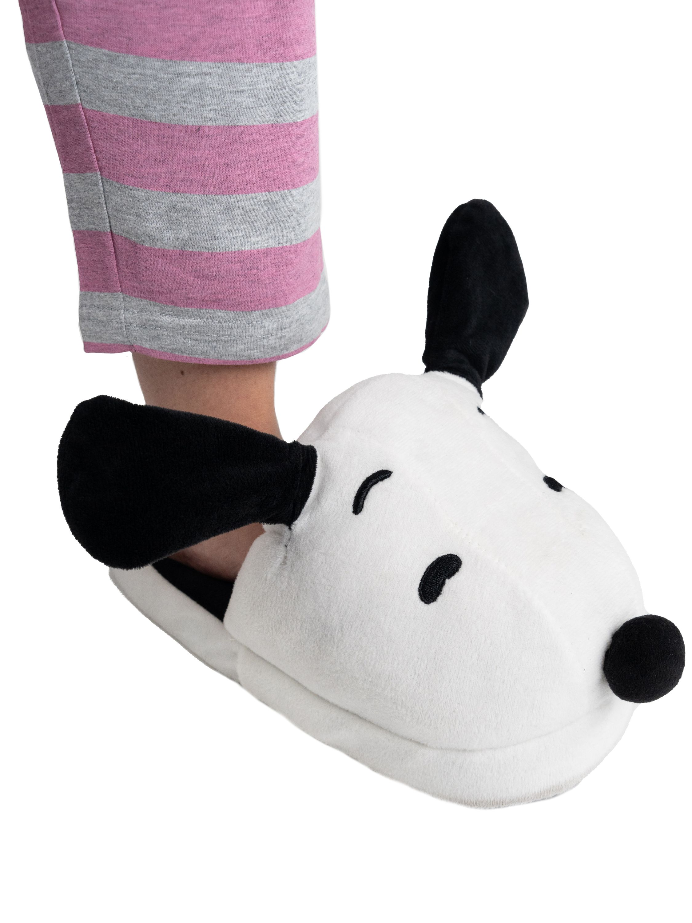 Ein weißer Snoopy-Pantoffelschuh mit schwarzen Ohren und Augen auf gestreiften Hosen.