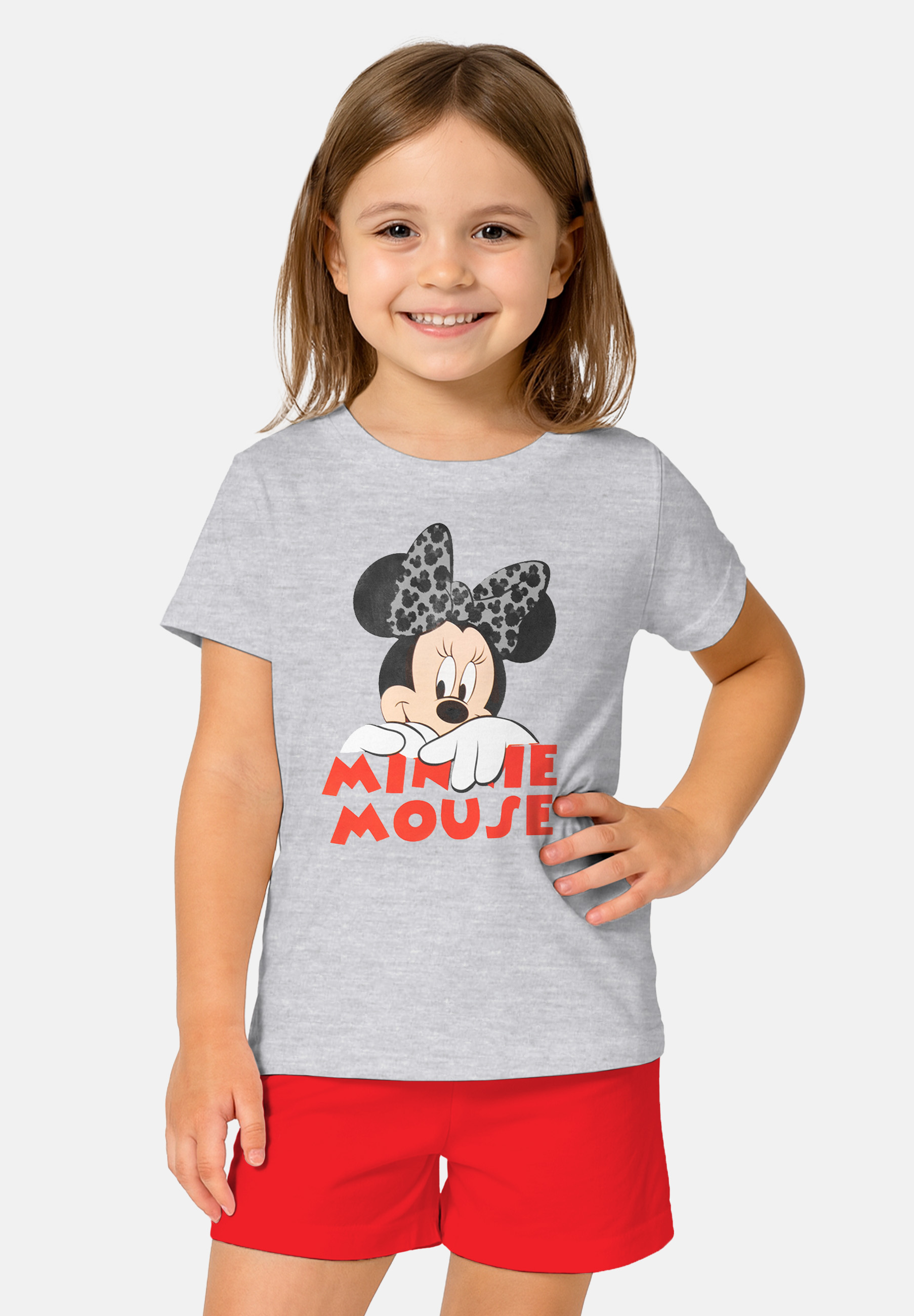 Ein Mädchen in einem grauen T-Shirt mit Minnie Maus und roten Shorts.