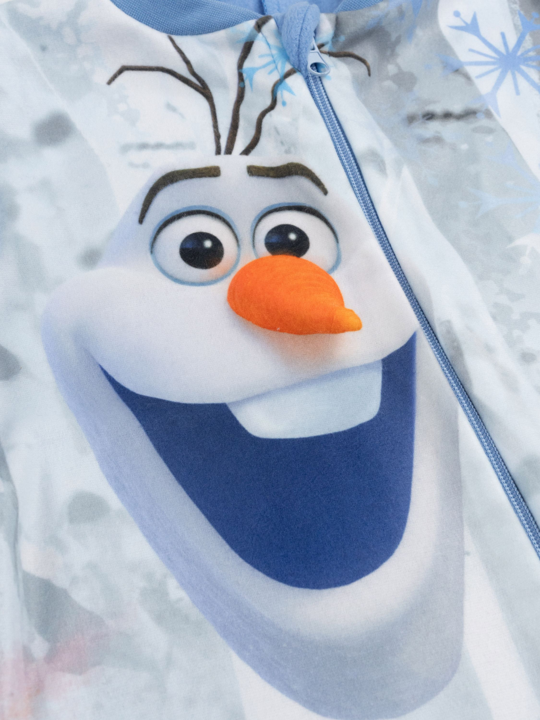 Olaf der Schneemann mit Karottennase auf einem blauen Reißverschluss-Schlafanzug.