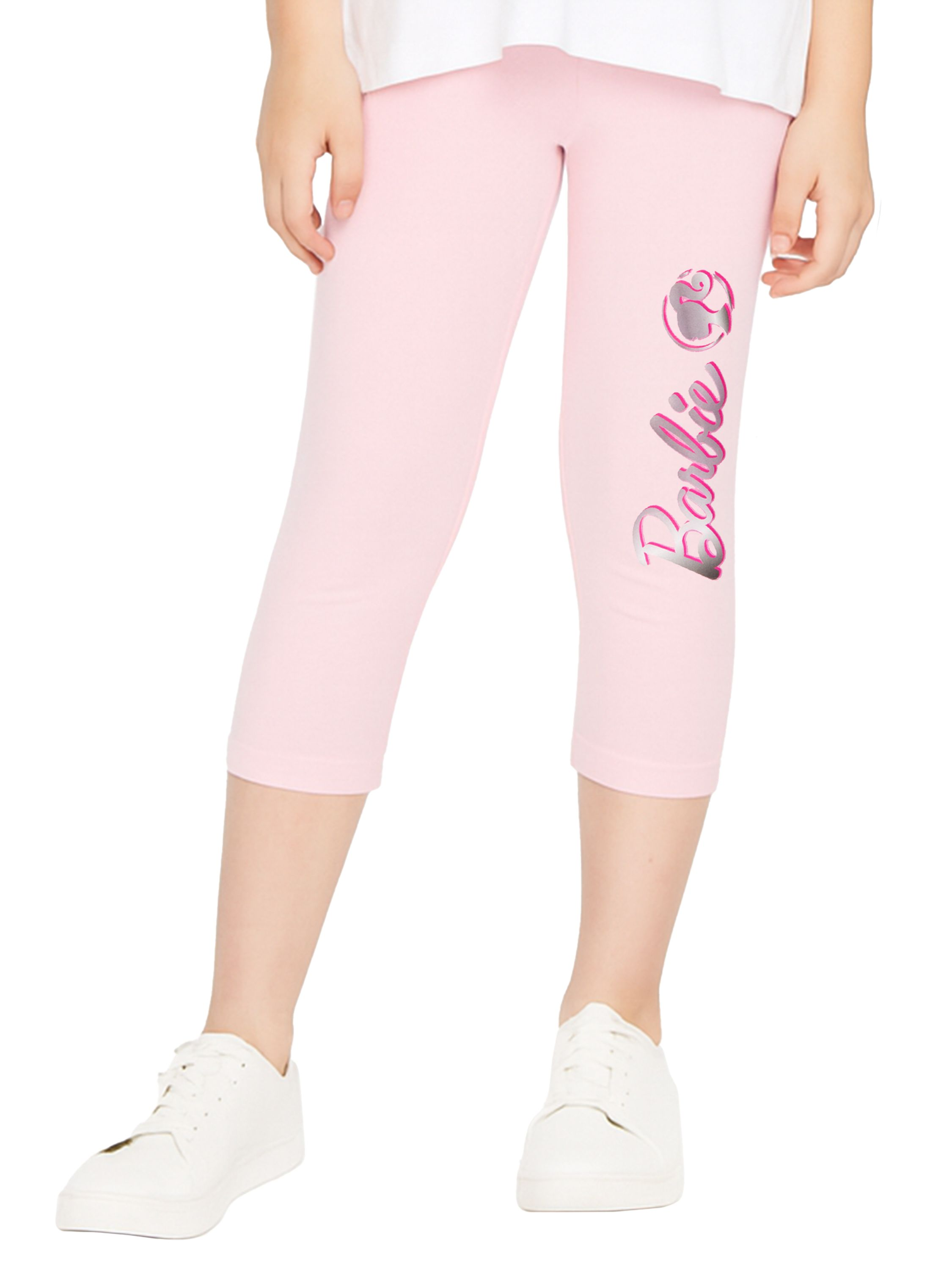 Ein Kind trägt eine rosafarbene Barbie-Leggings und weiße Turnschuhe.