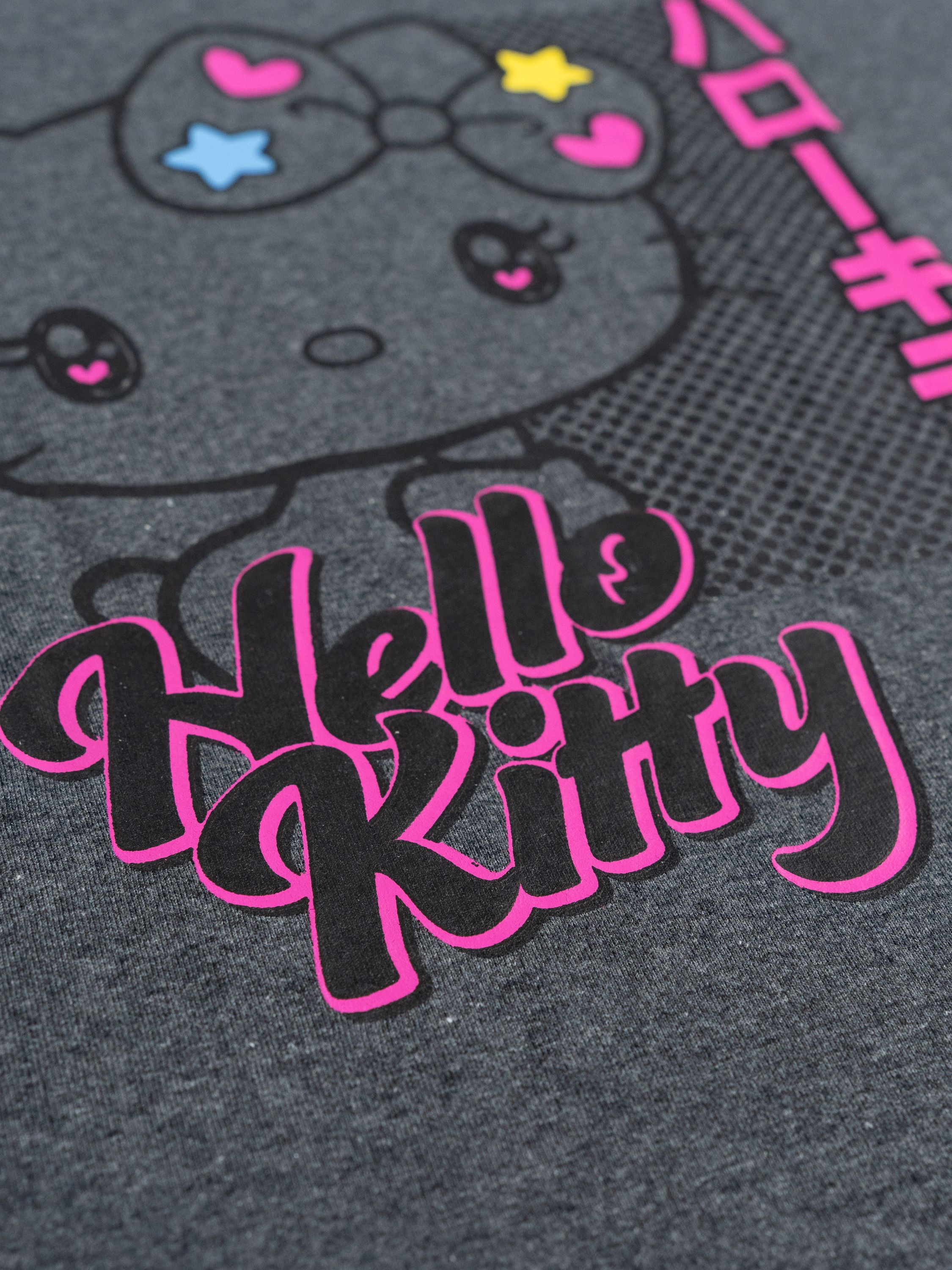 Grauer Stoff mit Hello Kitty Motiv und Schriftzug in Pink und Schwarz.