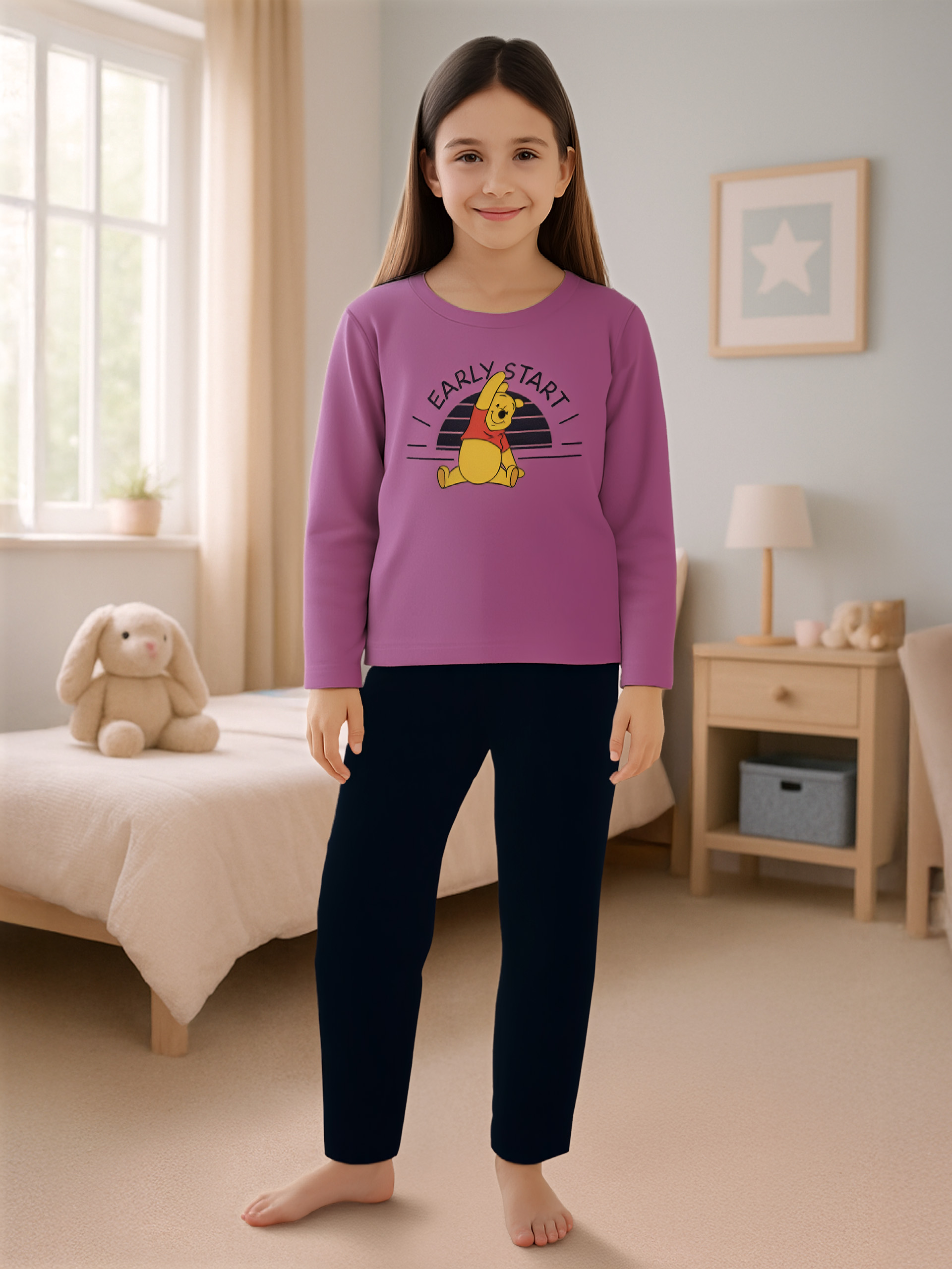 Ein Mädchen in lila Pyjama mit Winnie Puuh-Aufdruck und dunklen Hosen.