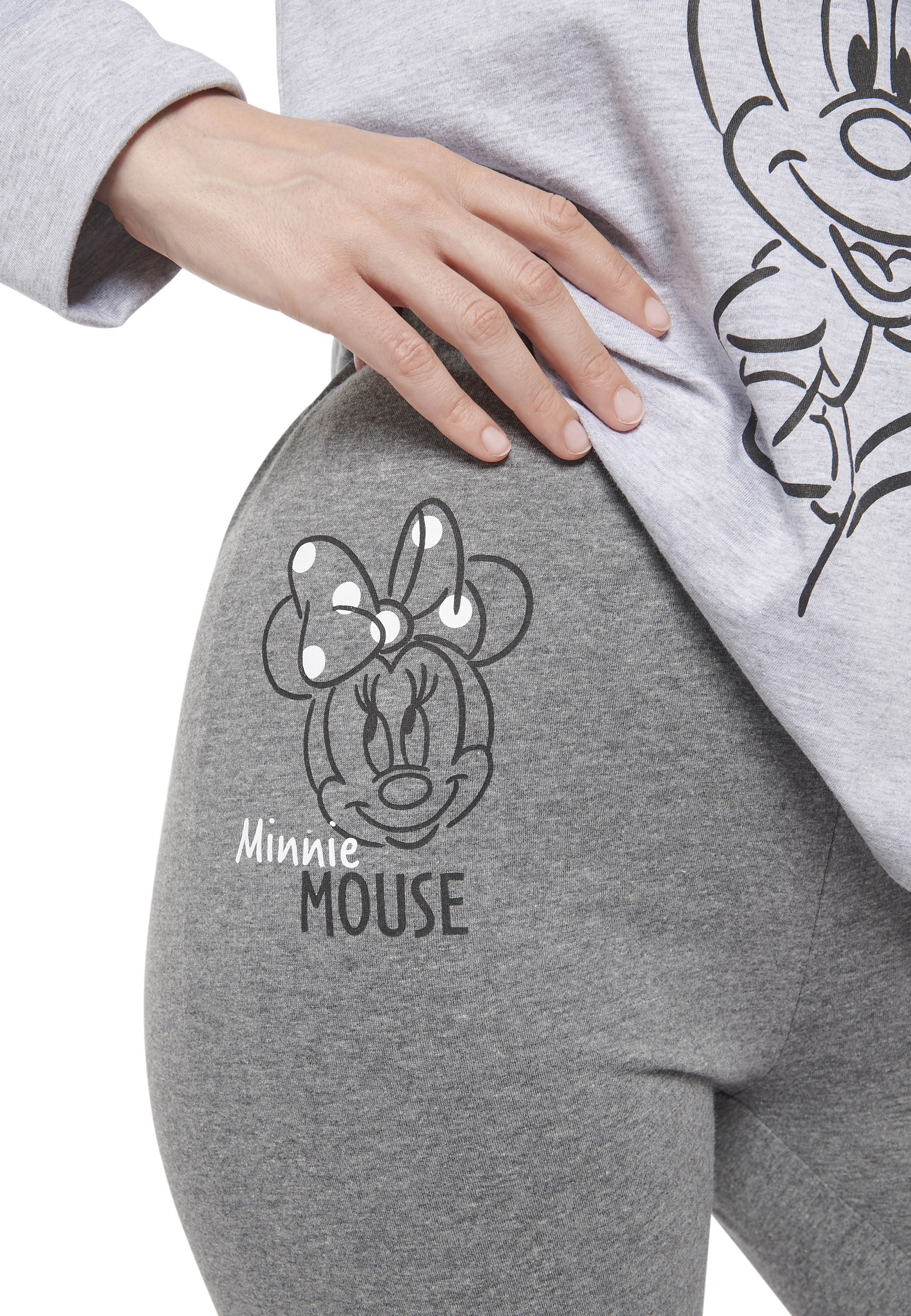 Graue Hose mit Minnie Maus-Aufdruck und einer Hand auf der Hüfte.