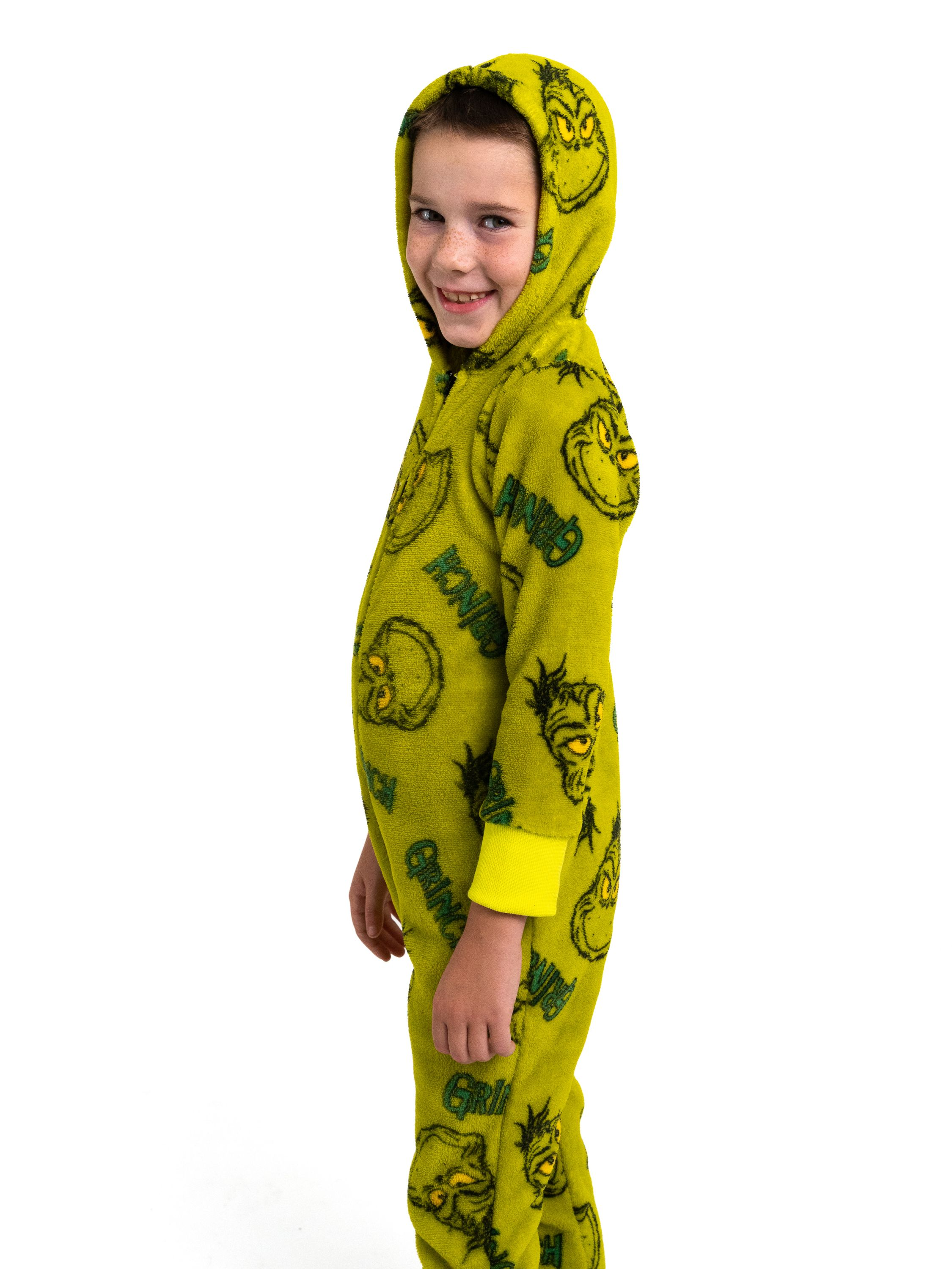 Ein Junge in einem Grinch-Pyjama steht vor weißem Hintergrund.