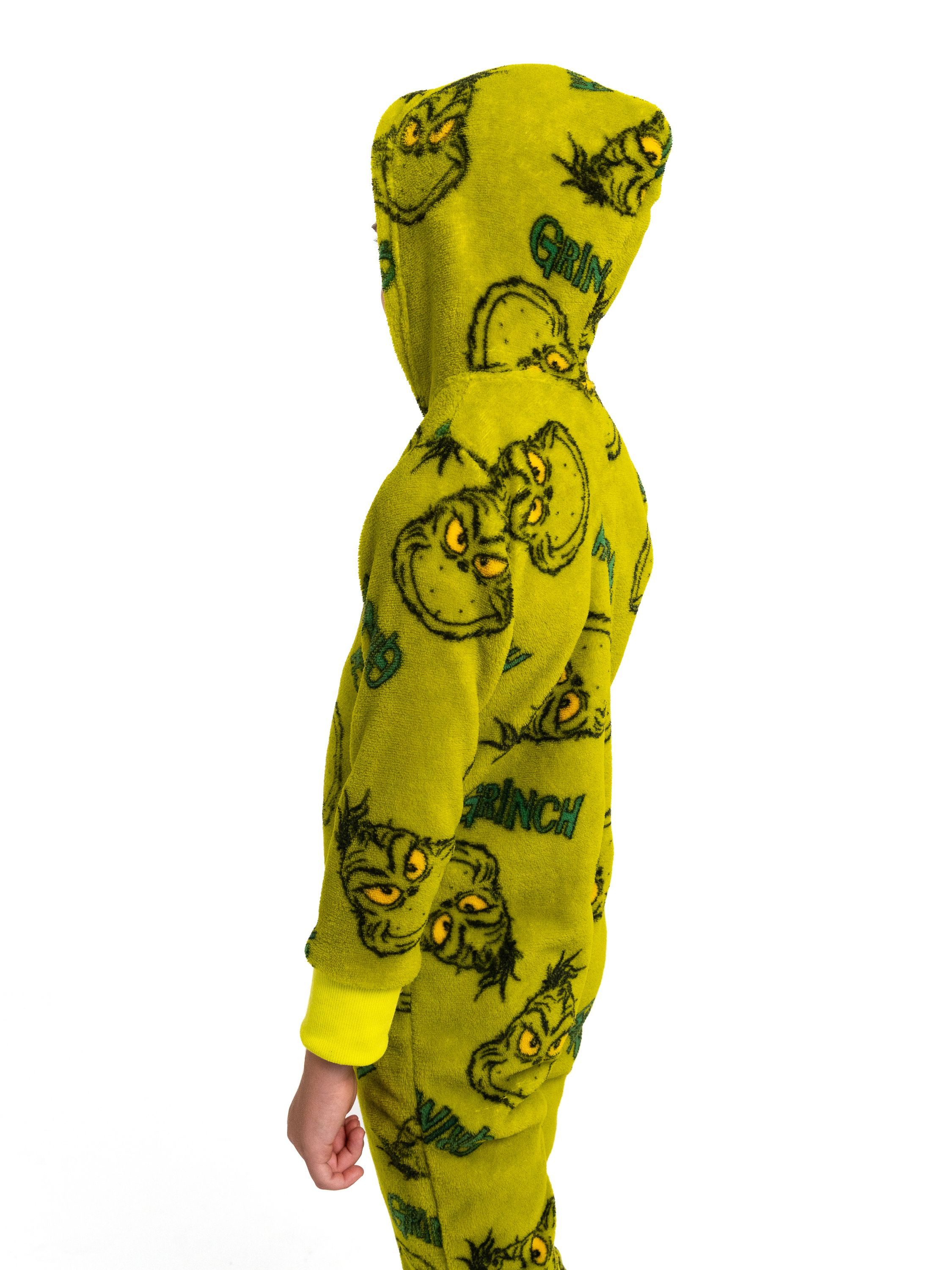 Ein Kind trägt einen gelben Strampelanzug mit Grinch-Aufdruck.