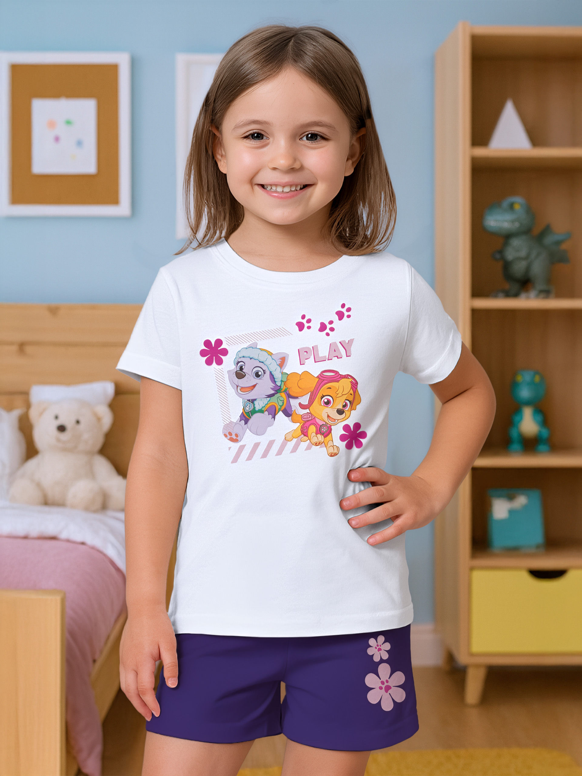 Ein Mädchen in einem weißen T-Shirt mit Paw Patrol-Aufdruck und violetten Shorts.