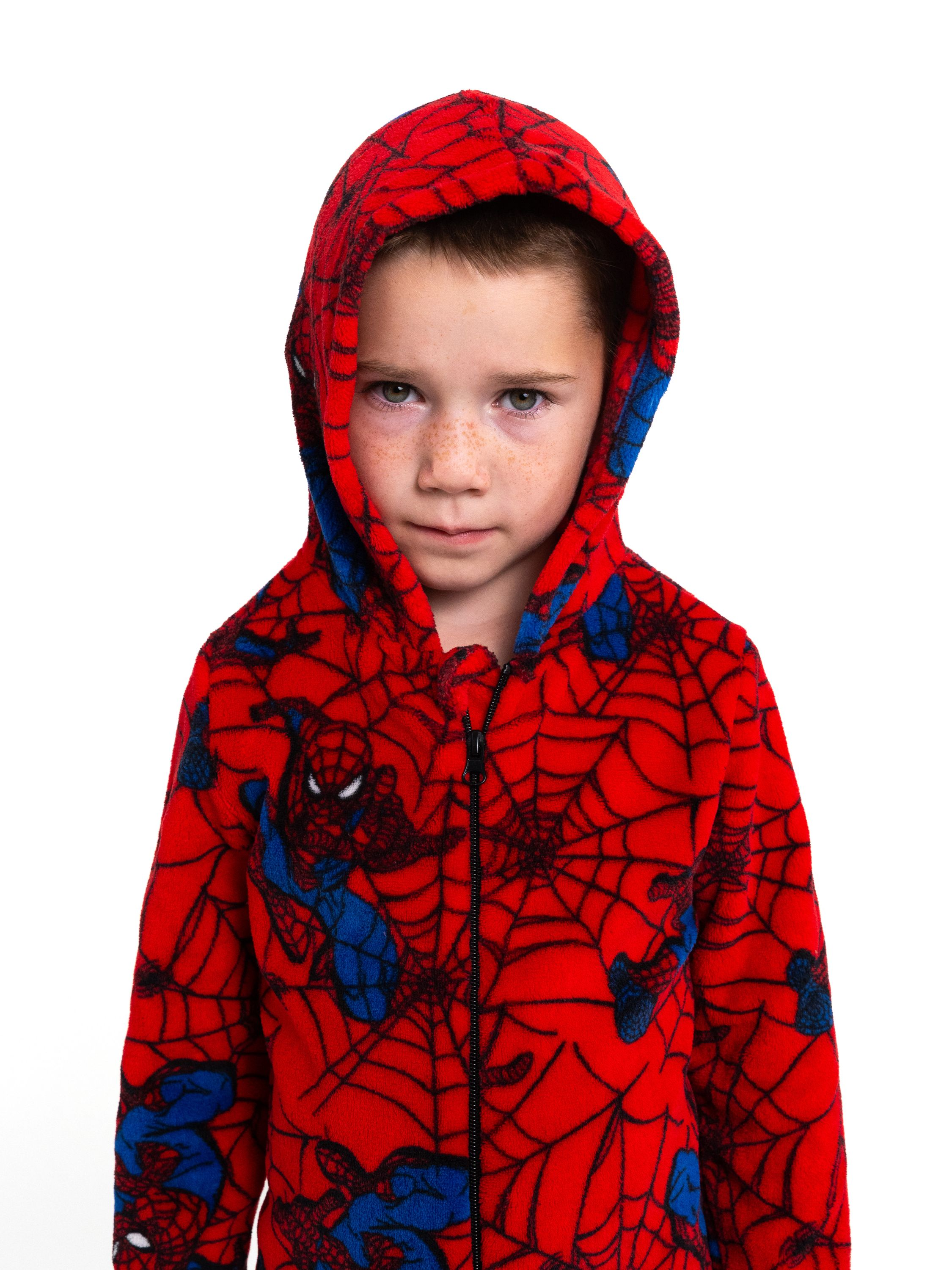 Ein Junge mit Sommersprossen trägt einen roten Pyjama mit Spiderman-Motiv.