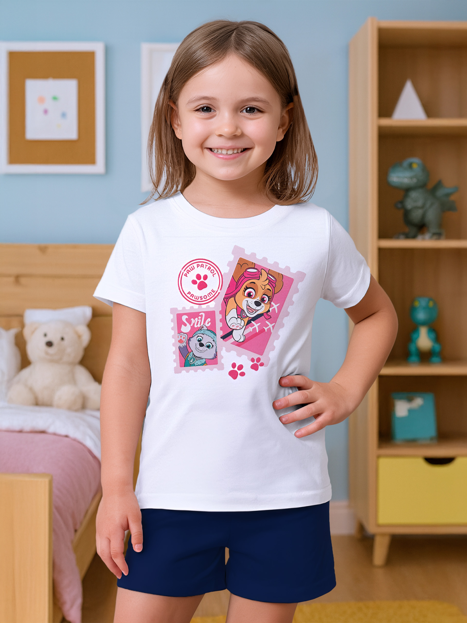 Ein Mädchen trägt ein weißes T-Shirt mit Paw Patrol-Aufdruck und blauen Shorts.