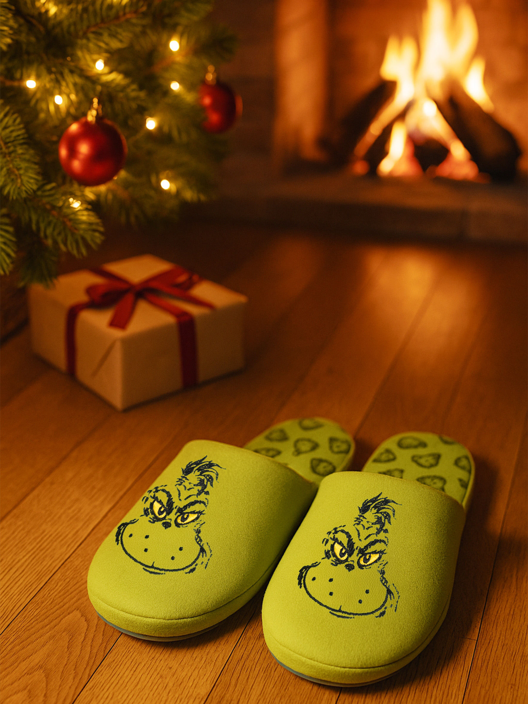 Grüne Grinch-Hausschuhe, ein Geschenk und ein Kaminfeuer.