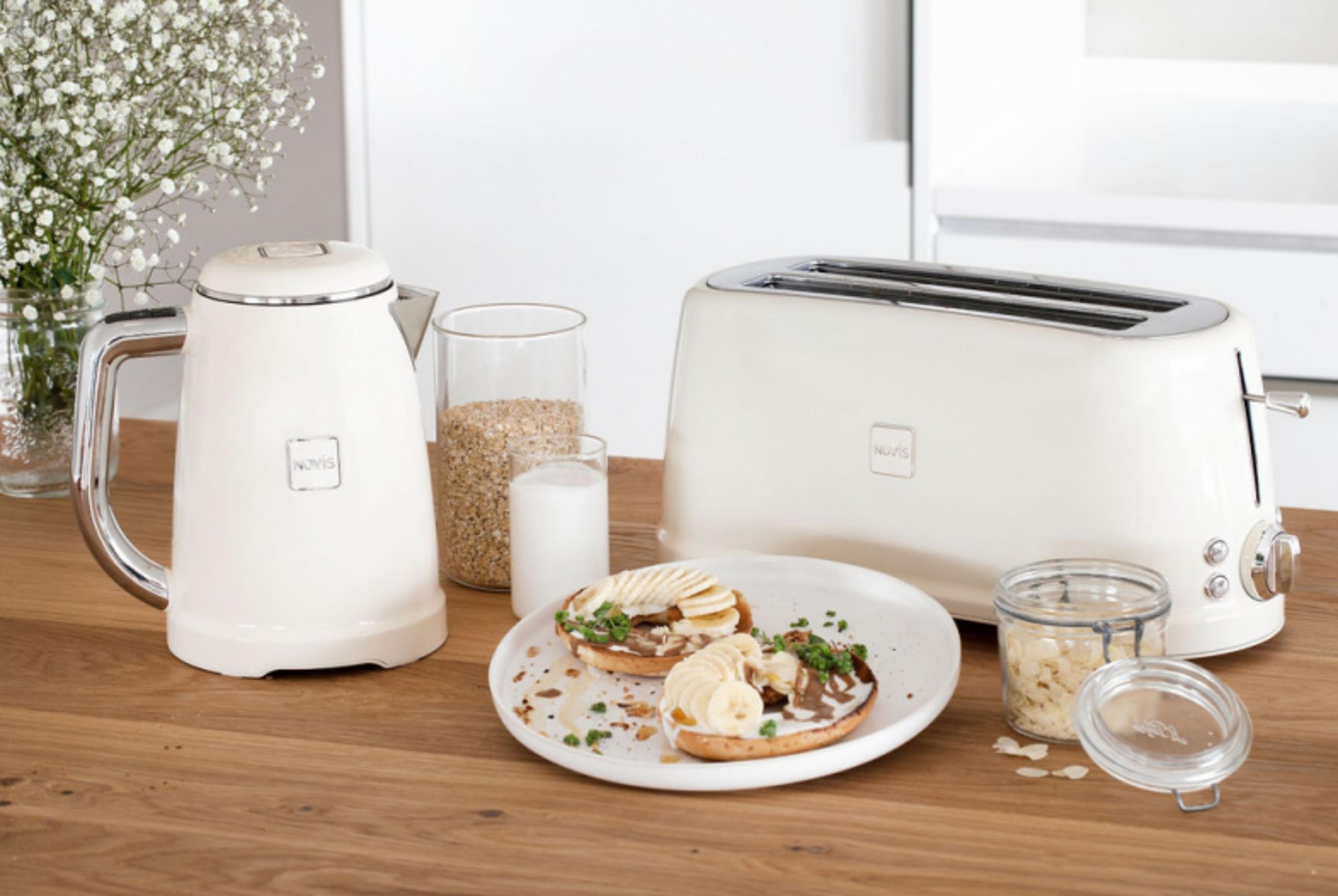 Eine weiße Teekanne, ein Toaster, ein Teller mit Bagels und Gläser mit Haferflocken.