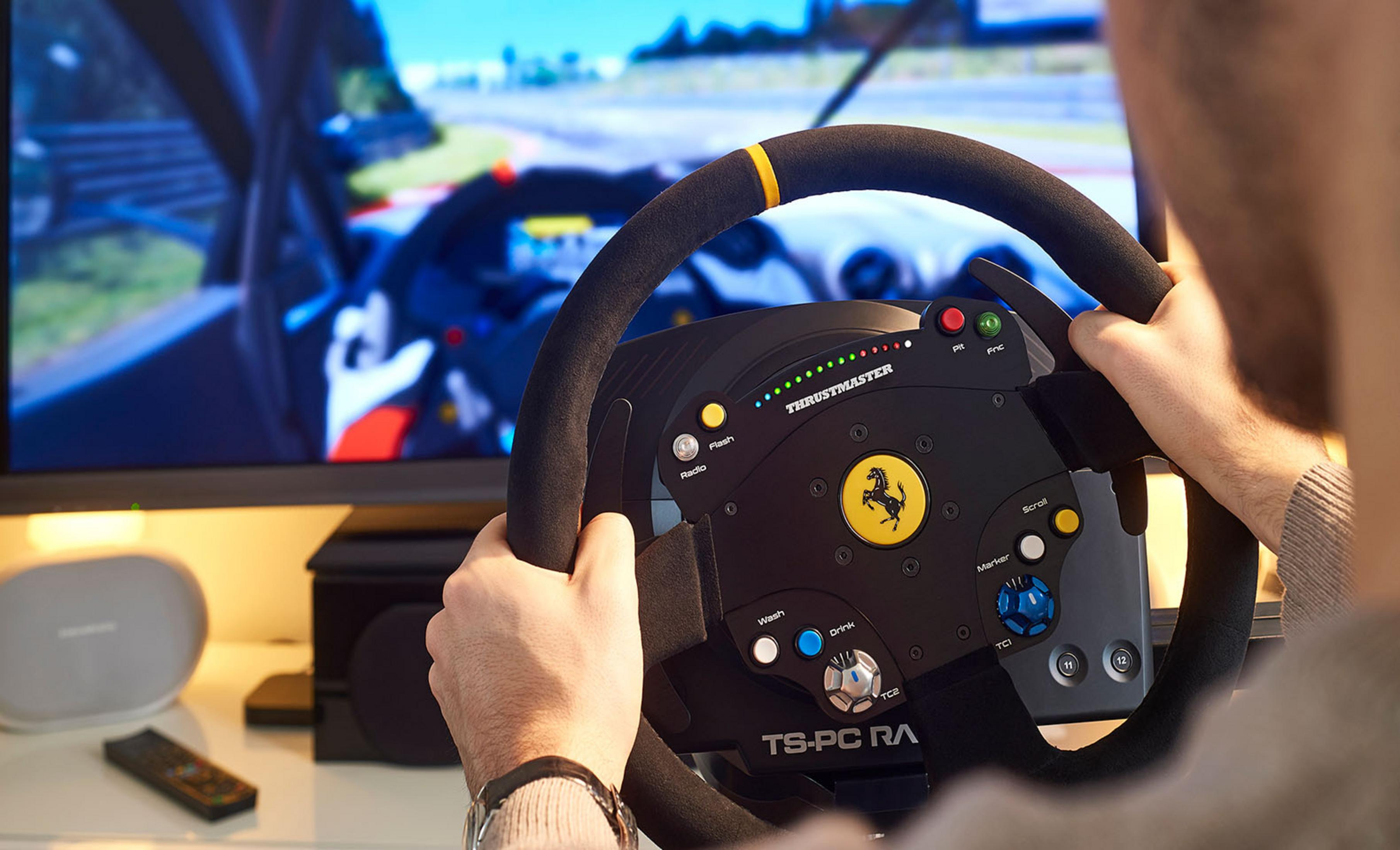 Ein Mann spielt ein Rennspiel mit einem Thrustmaster-Lenkrad. Der Bildschirm zeigt eine Rennstrecke.