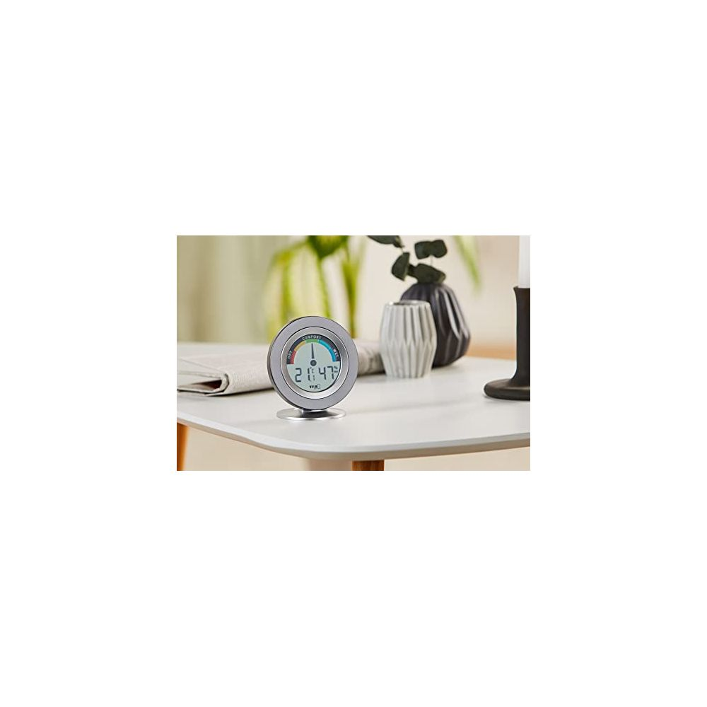 Runder Thermometer/Hygrometer auf Tisch mit zwei Vasen und Buch.