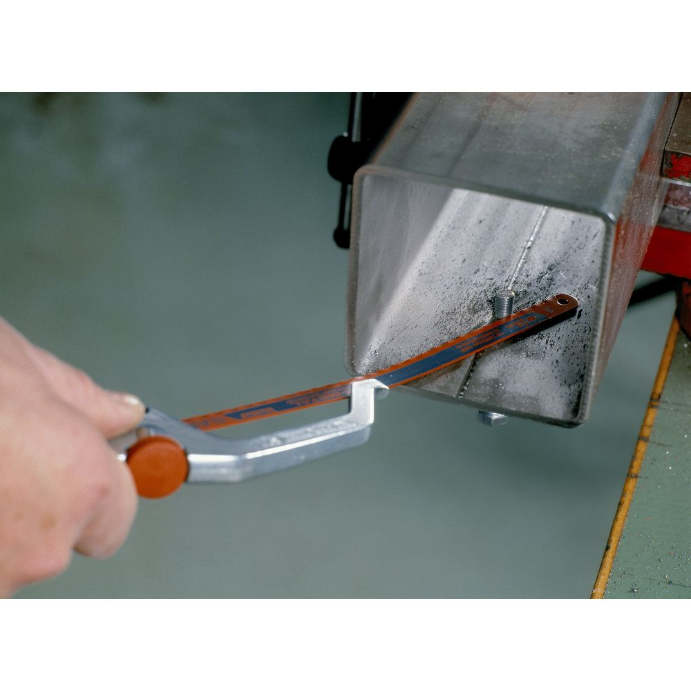 Dłoń trzyma piłę do metalu, przecinając metalową rurę.