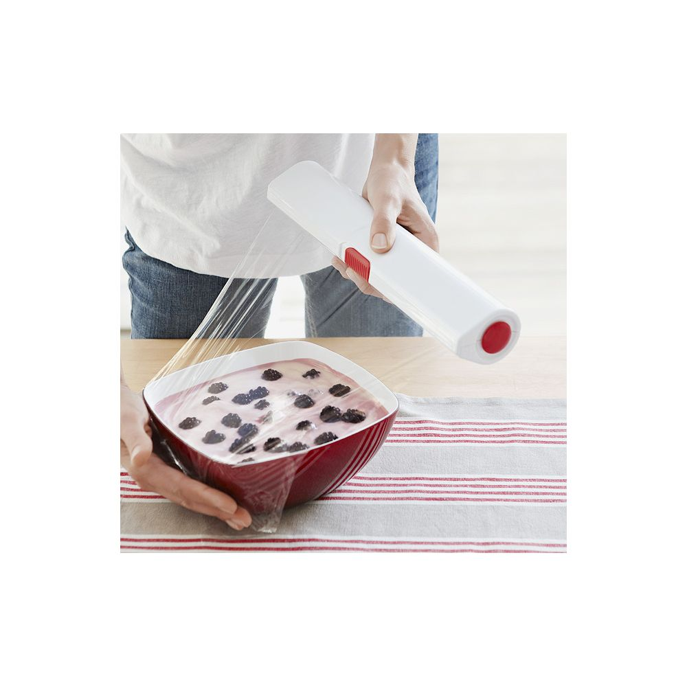 Eine Person wickelt eine Schüssel mit Beeren in Frischhaltefolie ein.