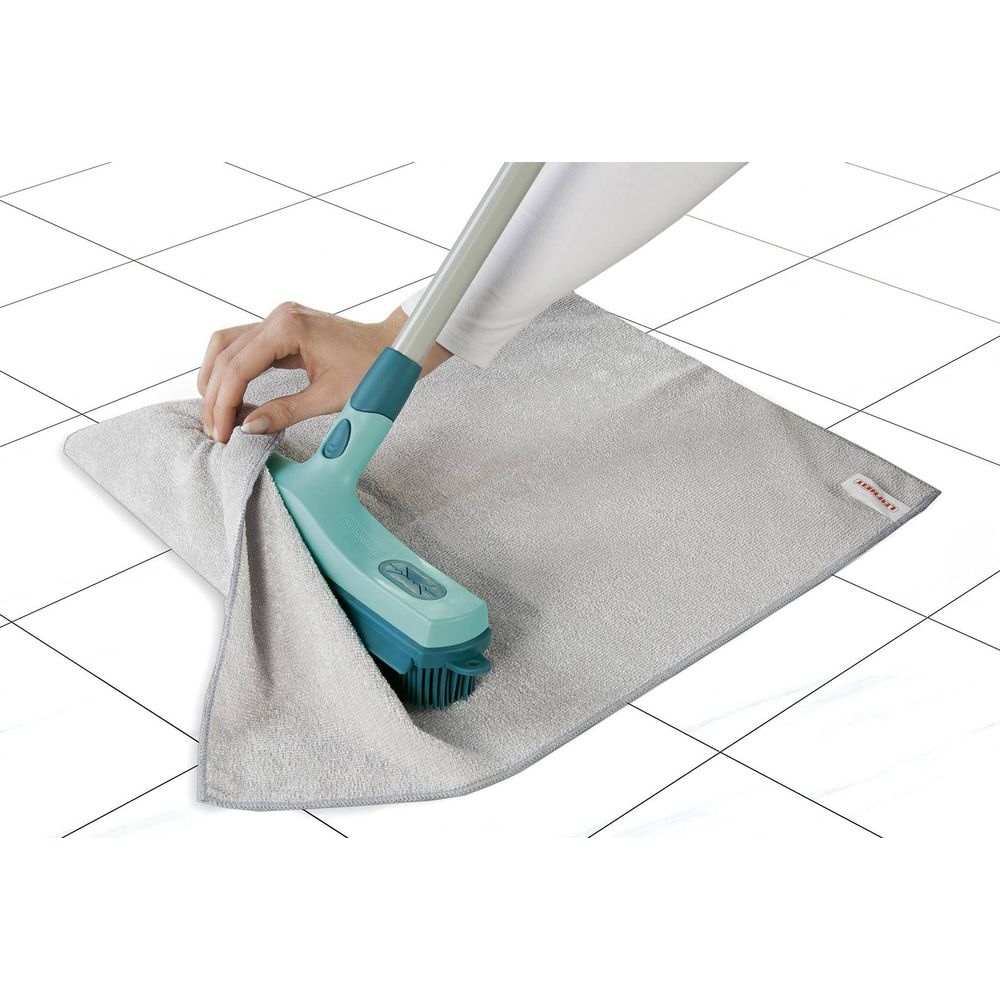 Una mano usa una spazzola per fissare un panno in microfibra grigio su un pavimento piastrellato.