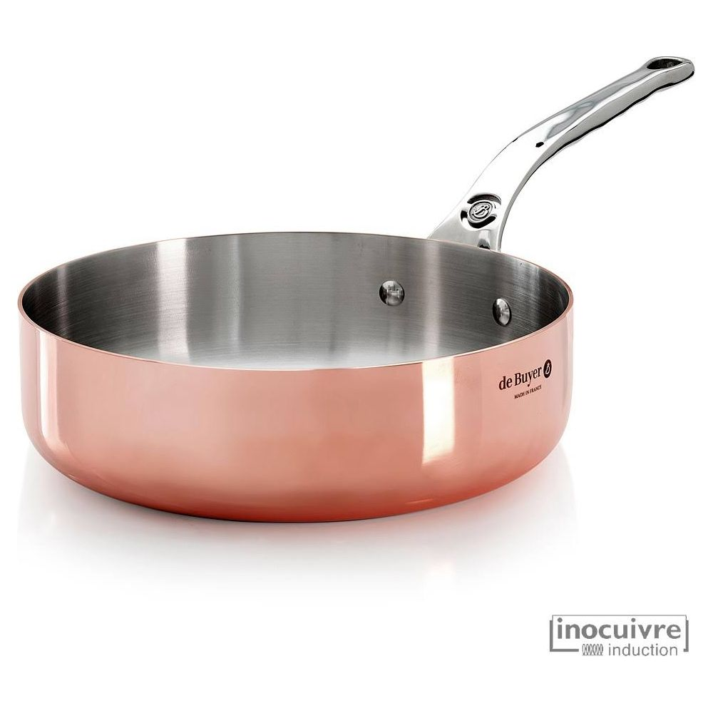 Miedziana patelnia z polerowaną metalową rączką, na białym tle.