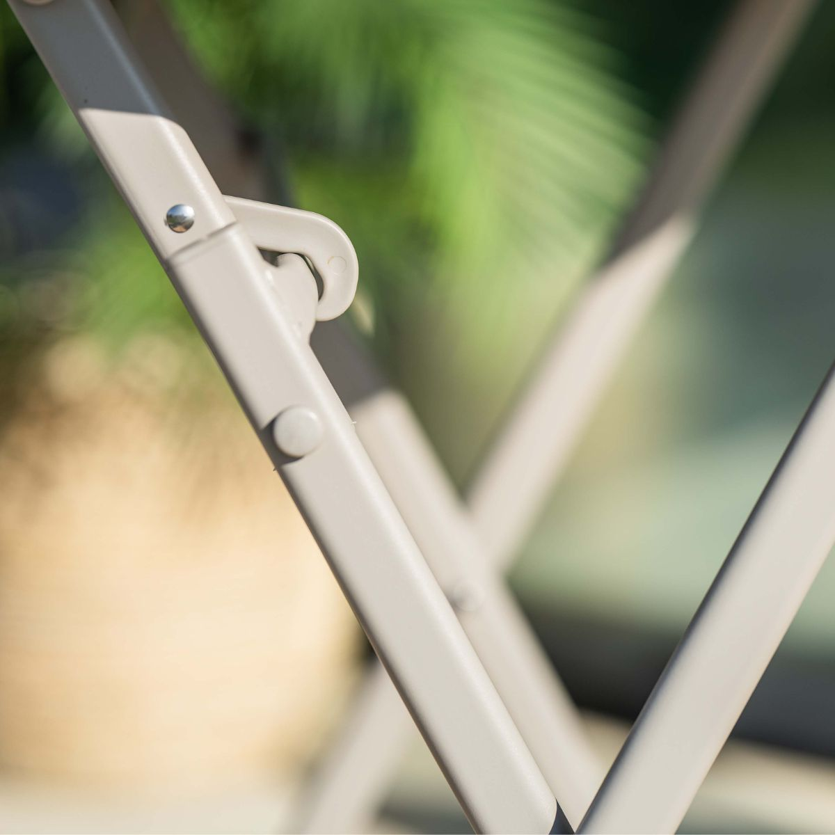 Close-up van een lichtbeige opvouwbare metalen structuur met klinknagels en een scharnier.