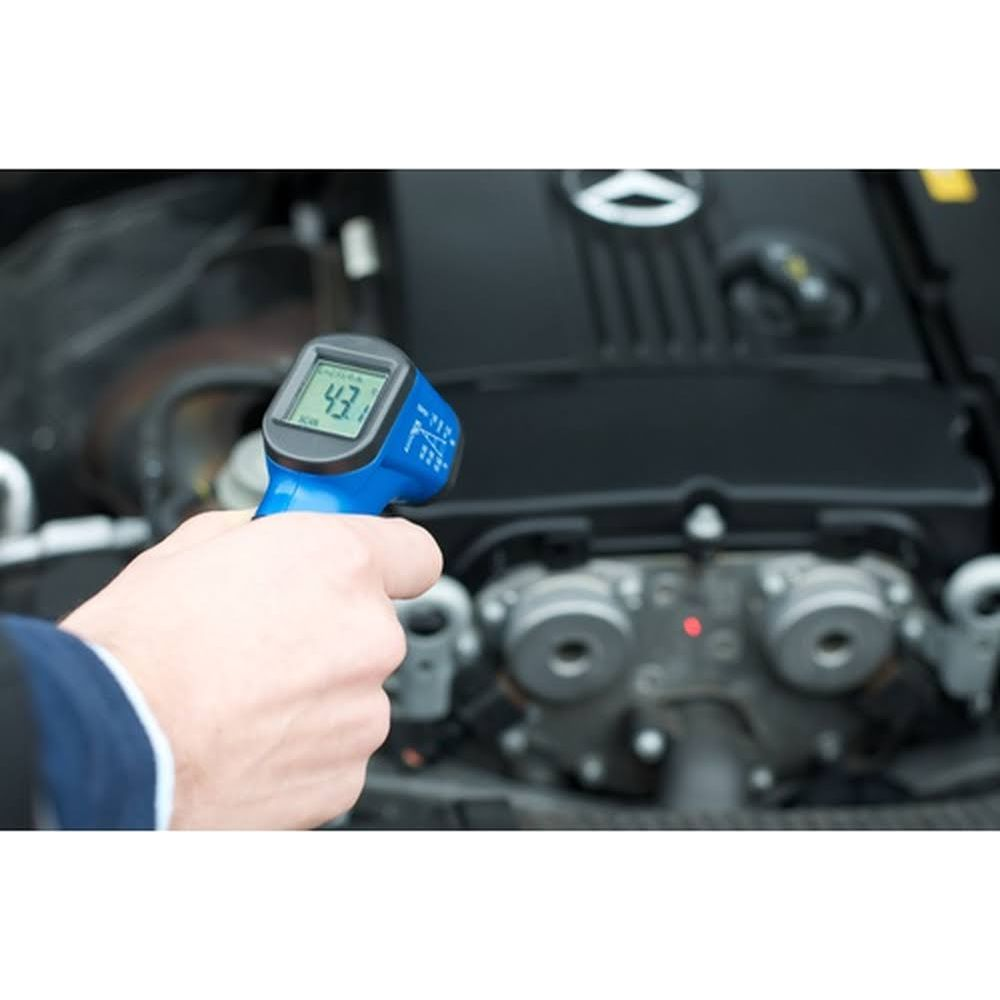 Ein Mann misst die Temperatur eines Motors mit einem blauen Thermometer.