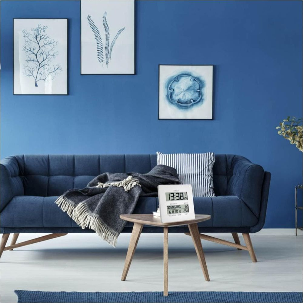 Ein blaues Sofa mit Decke und Kissen, drei Bilder an der Wand.