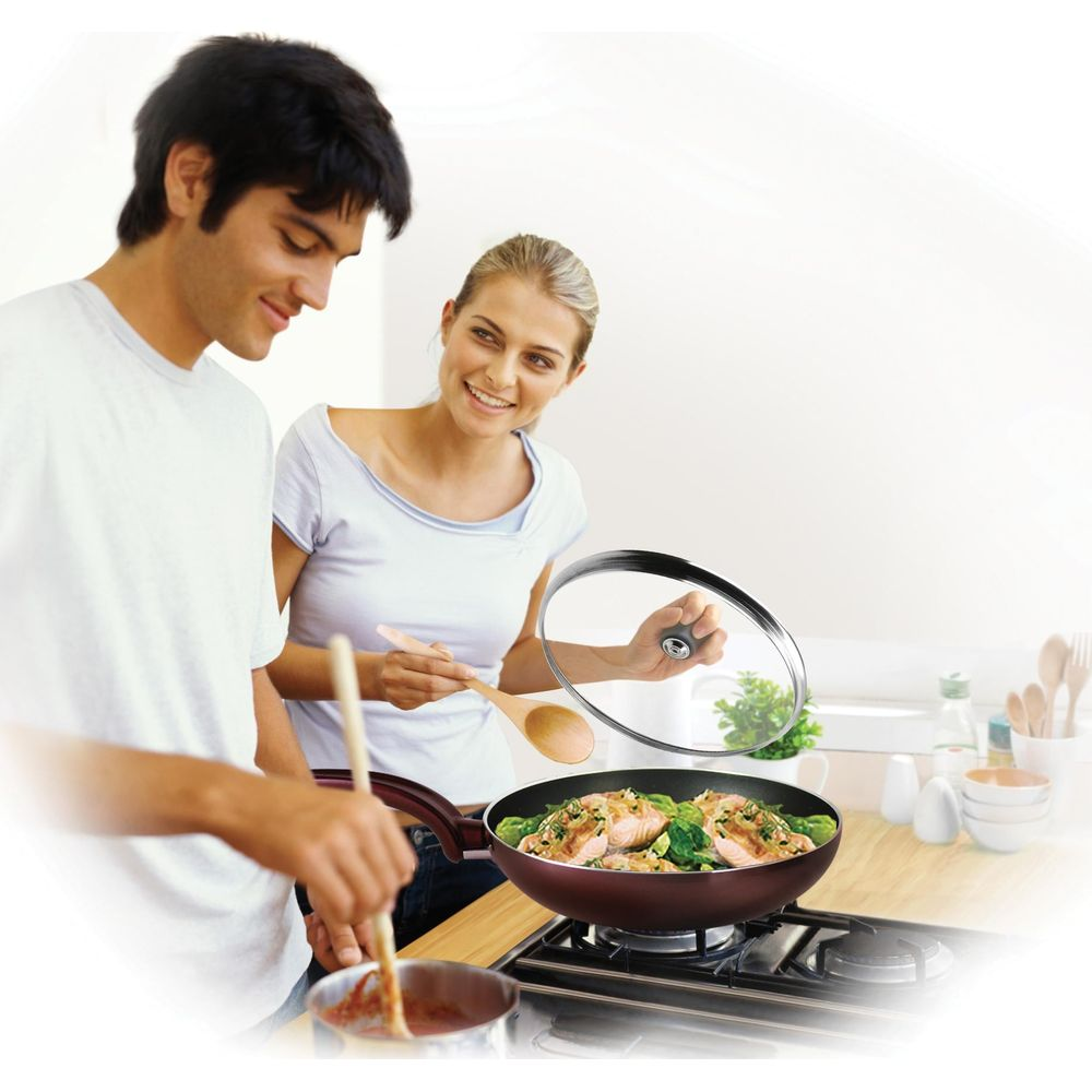 Mann und Frau kochen Lachs mit Brokkoli in einer Pfanne.
