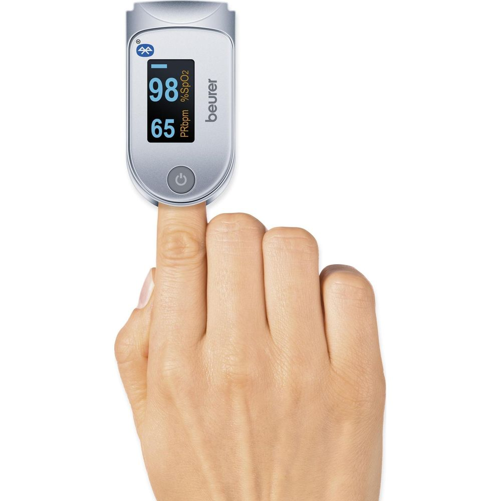 Ein Finger misst Sauerstoffgehalt und Puls mit einem silbernen Beurer-Pulsoximeter.